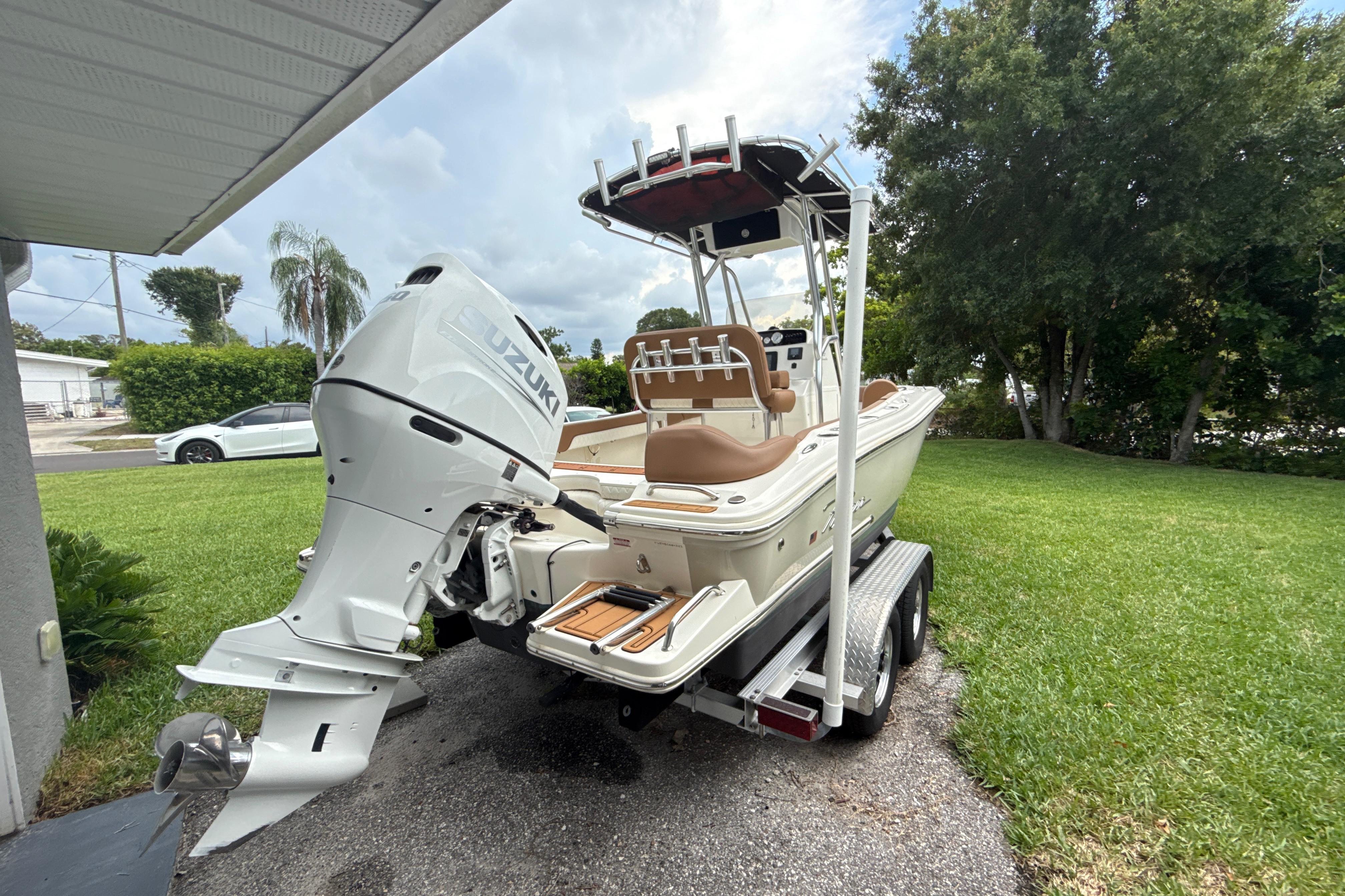2023 Pioneer 202 Islander boat with Suzuki outboard motor on trailer, parked in a driveway.