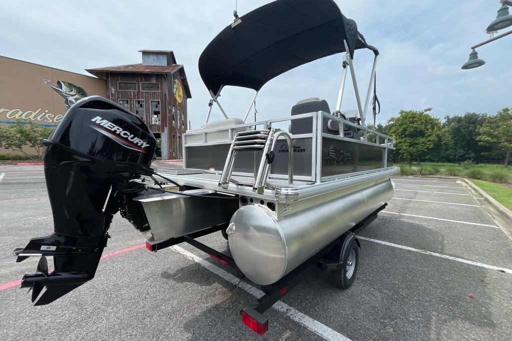 2026 Sun Tracker Bass Buggy 16 XL Select pontoon boat with Mercury engine in parking lot.