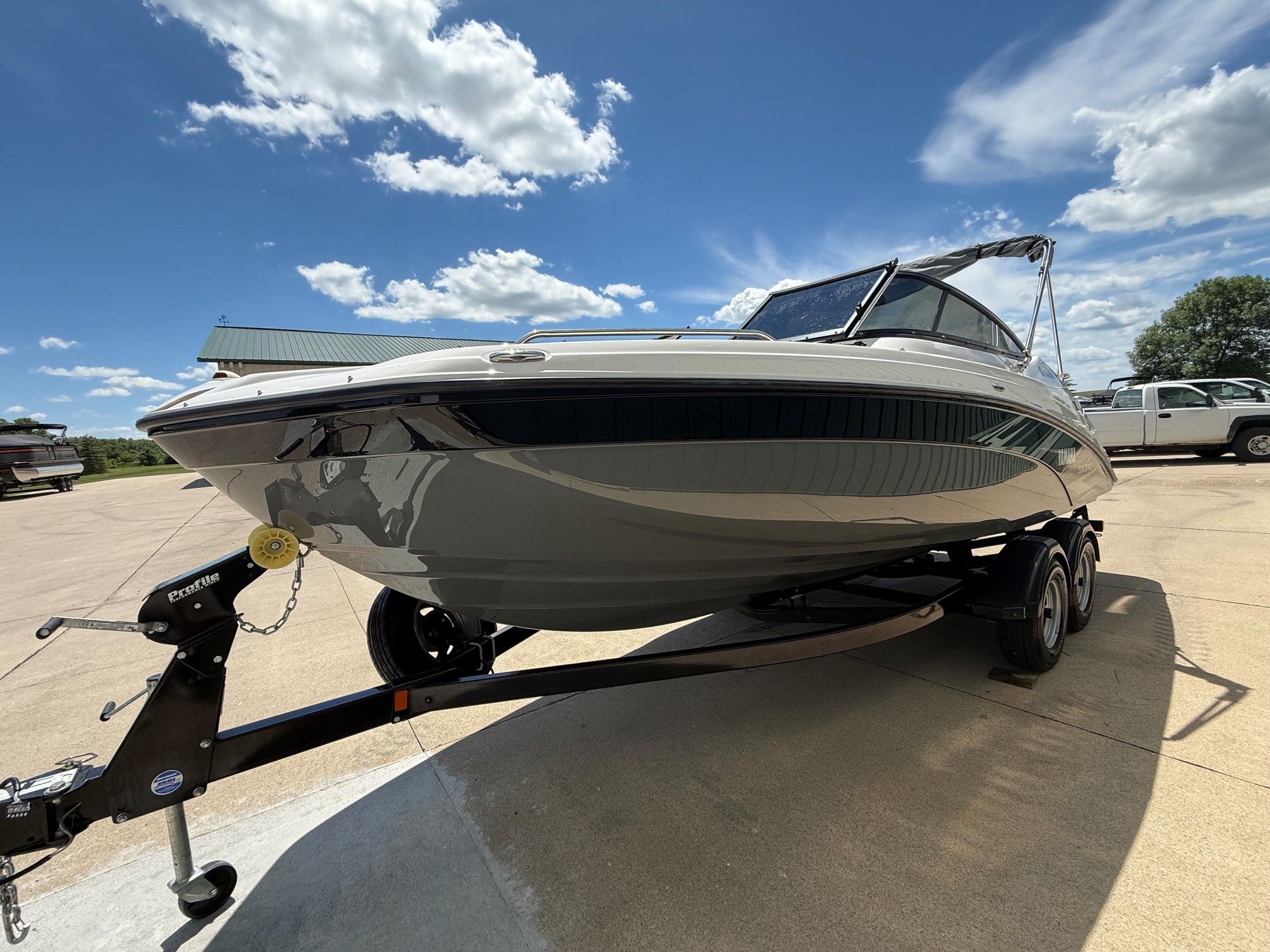 A Yamaha SX210 boat on a trailer, parked on a sunny lot.