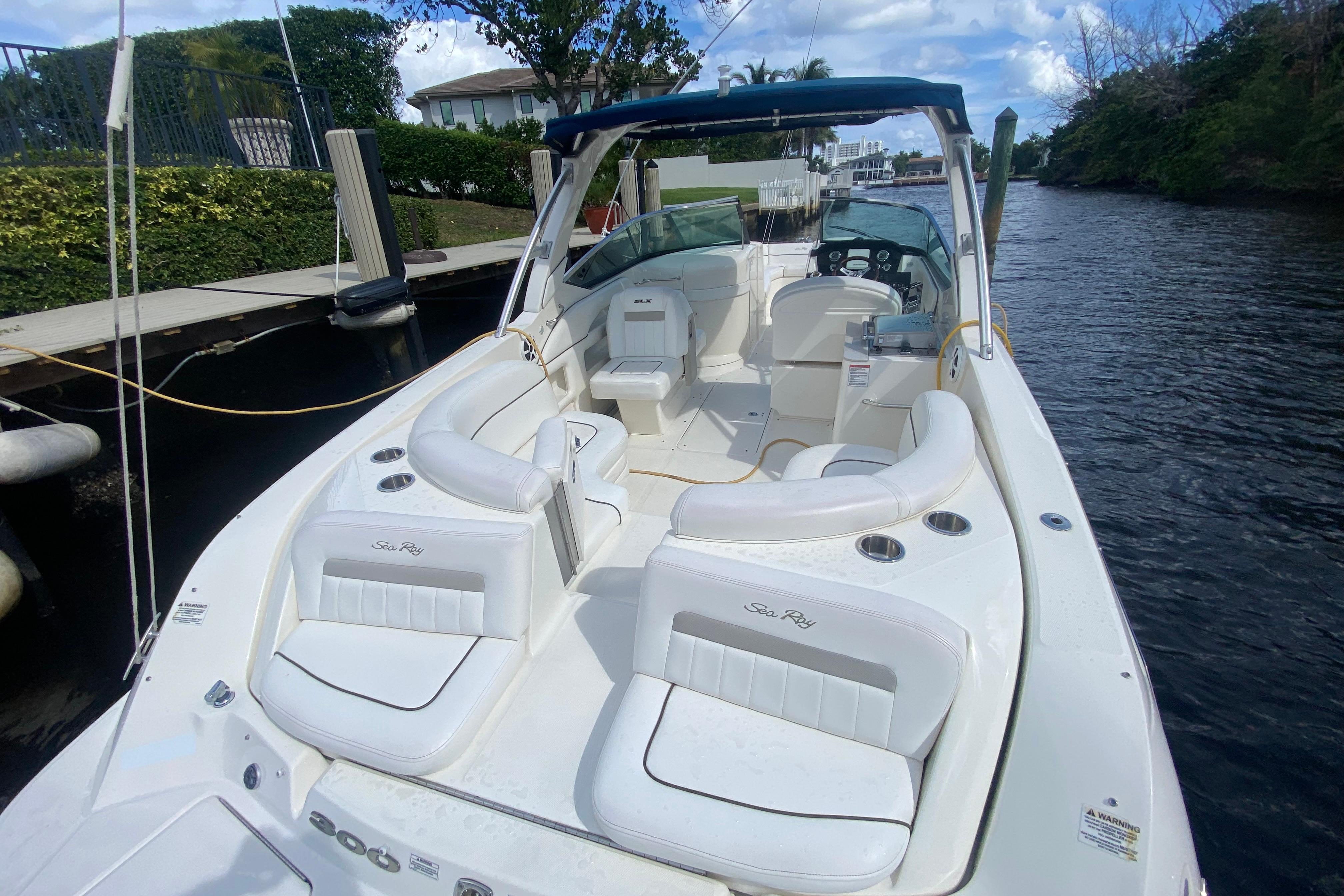 2010 Sea Ray 300 SLX boat with white seating, docked on a calm waterway.