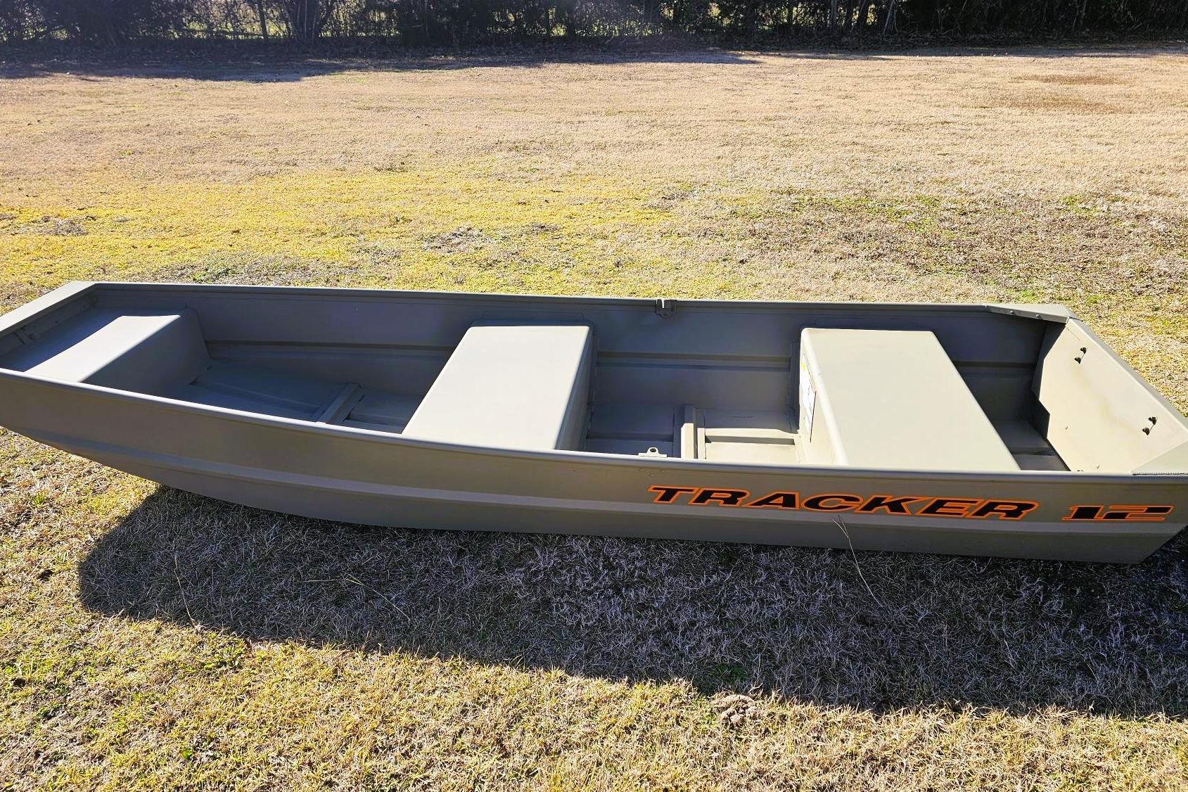 2026 Tracker Grizzly 12 Jon boat on grassy field, side view.