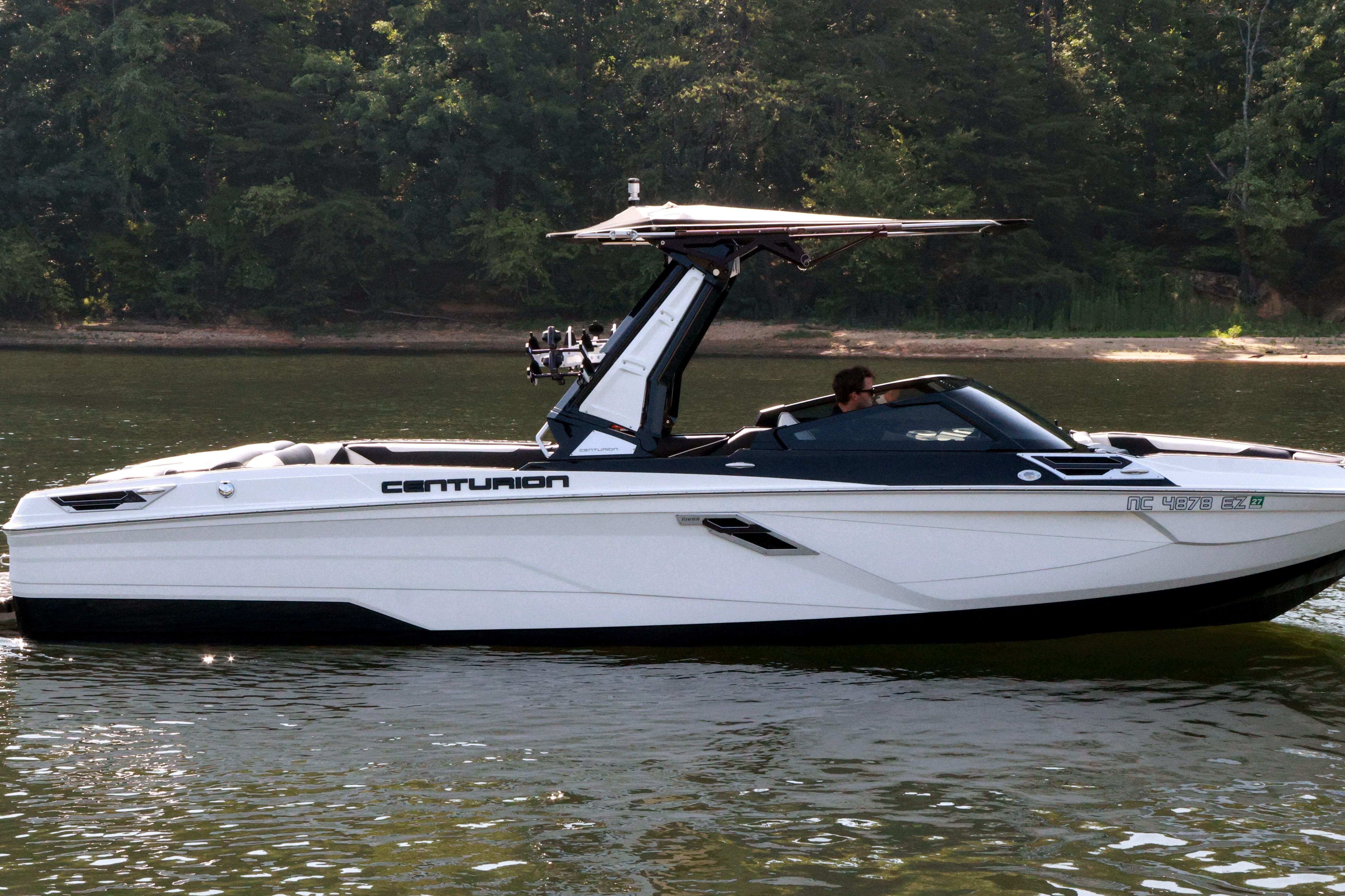 2022 Centurion Ri265 boat cruising on a calm lake with lush forest backdrop.