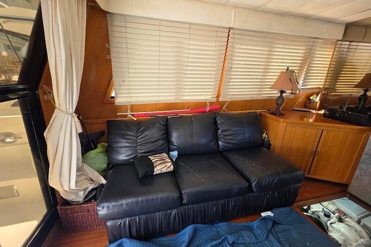 Interior of 1993 McKinna 48 Pilothouse with black leather sofa and wooden cabinetry.