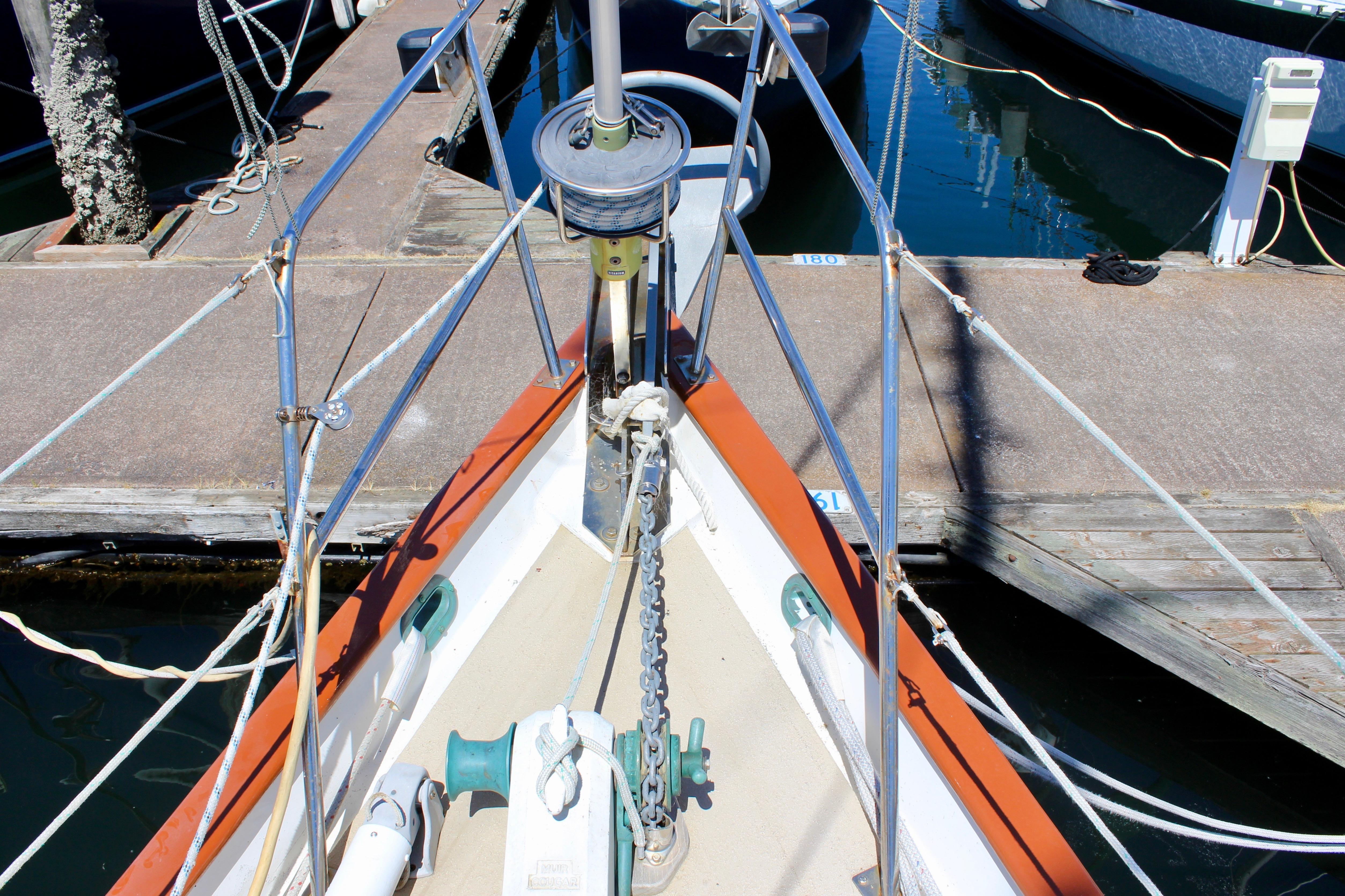 Bow of 1981 Kelly Peterson 46 sailboat docked at marina, showing anchor and winch.