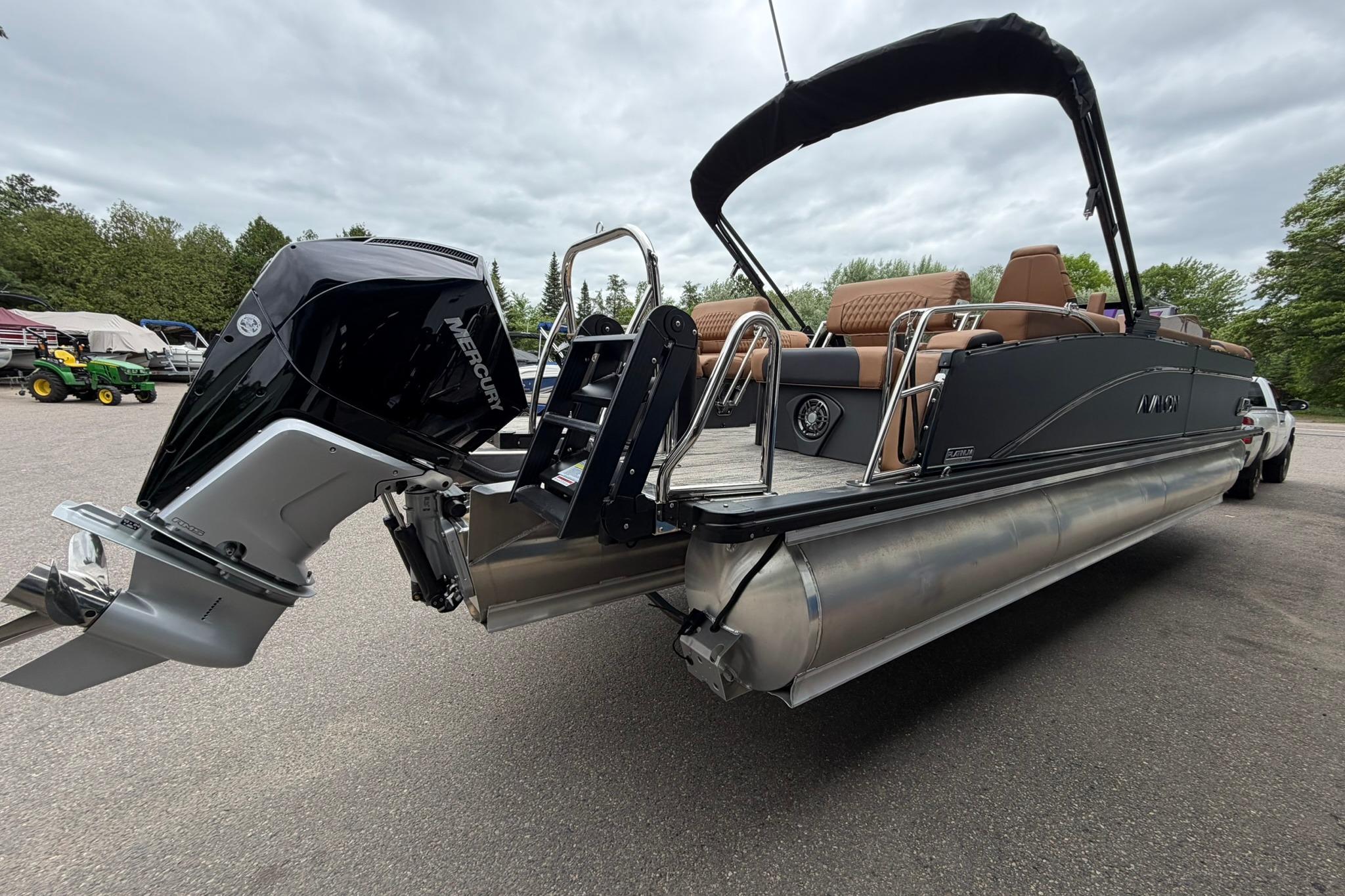 2026 Avalon Catalina Quad Lounge Shift boat with Mercury outboard motor, parked outdoors.