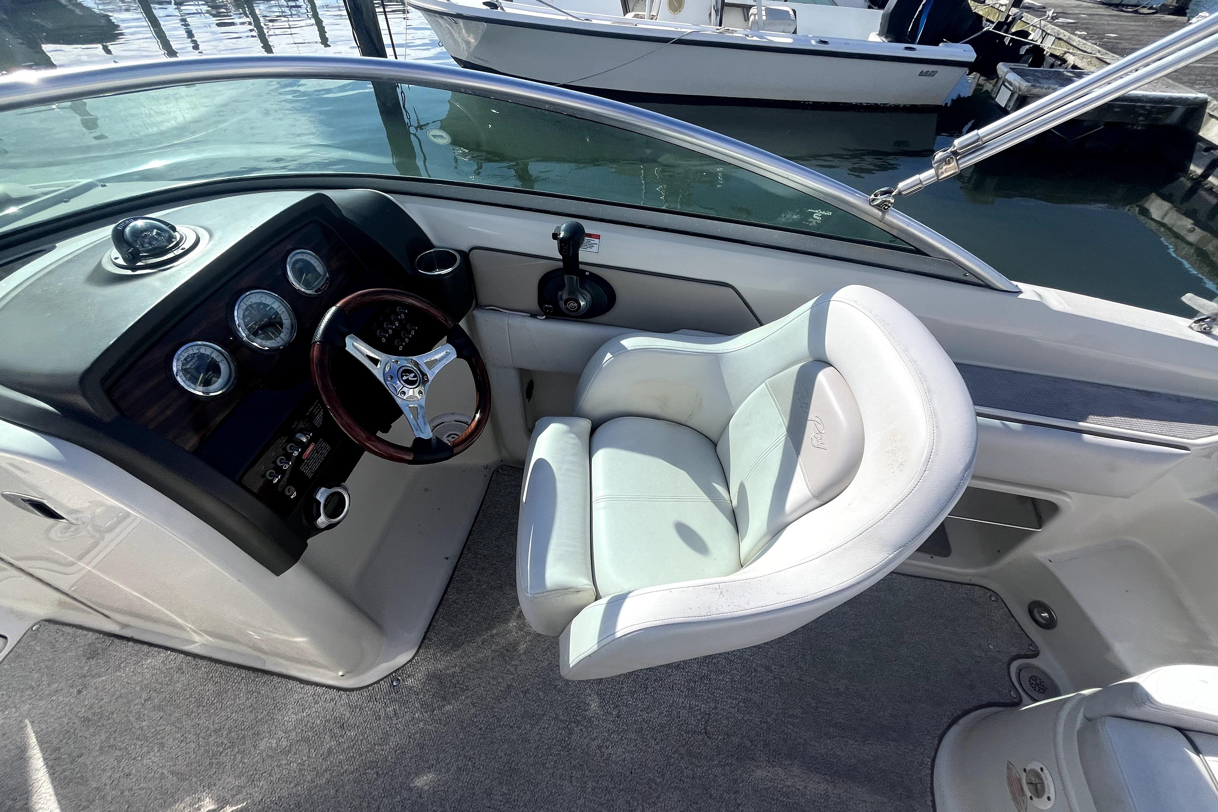 2010 Sea Ray 220 Sundeck cockpit with steering wheel and white captain's chair.