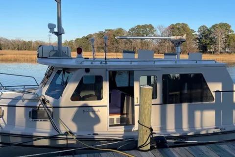 1997 Rosborough Trawler docked by a serene lakeside with clear blue skies.