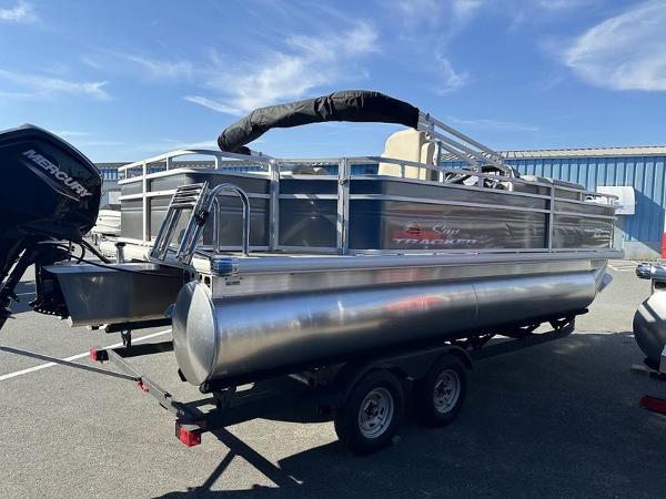 2025 Sun Tracker FB 20 DLX pontoon boat on trailer, parked outdoors.
