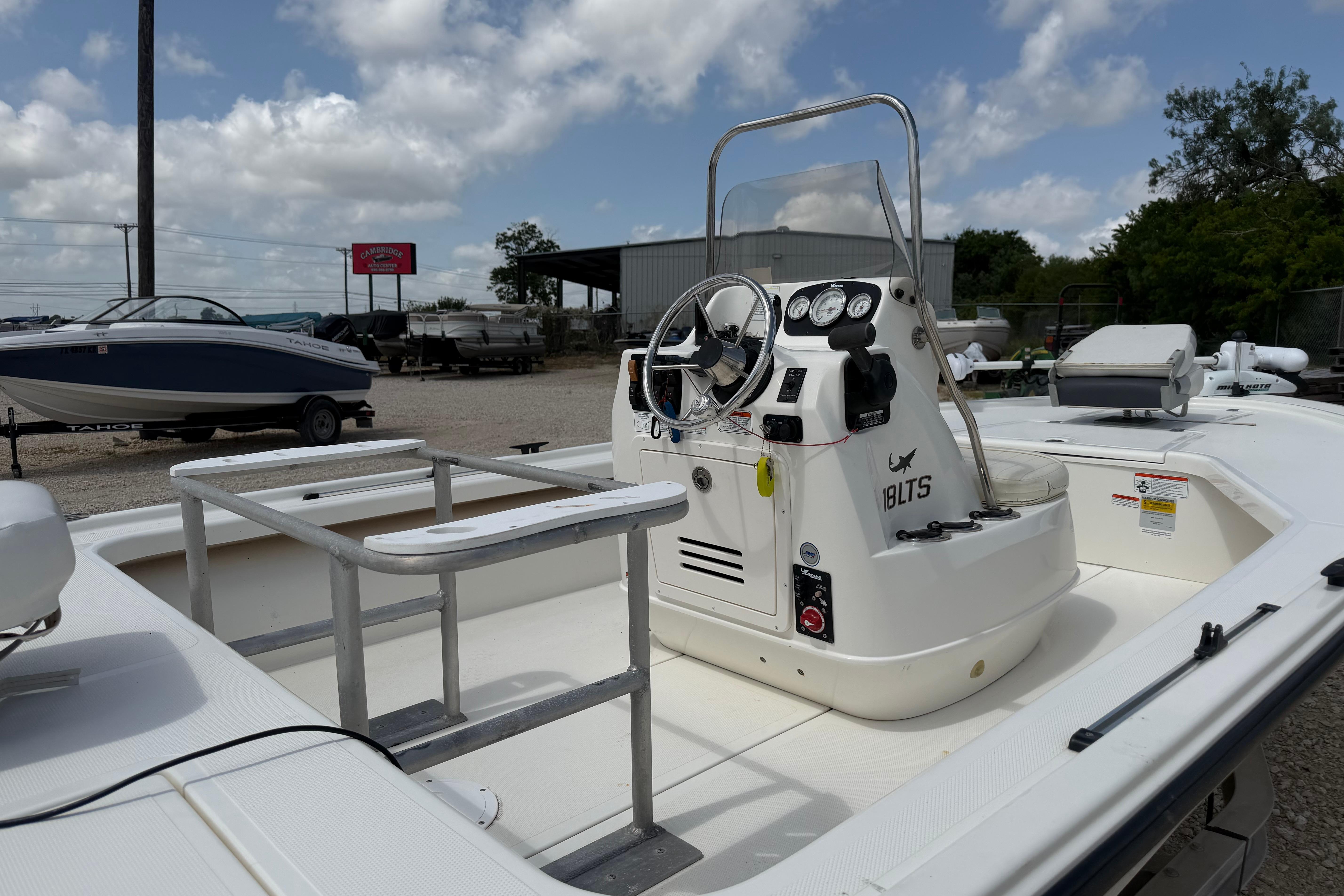 2012 Mako 18 LTS boat interior with steering console and seating, under a cloudy sky.