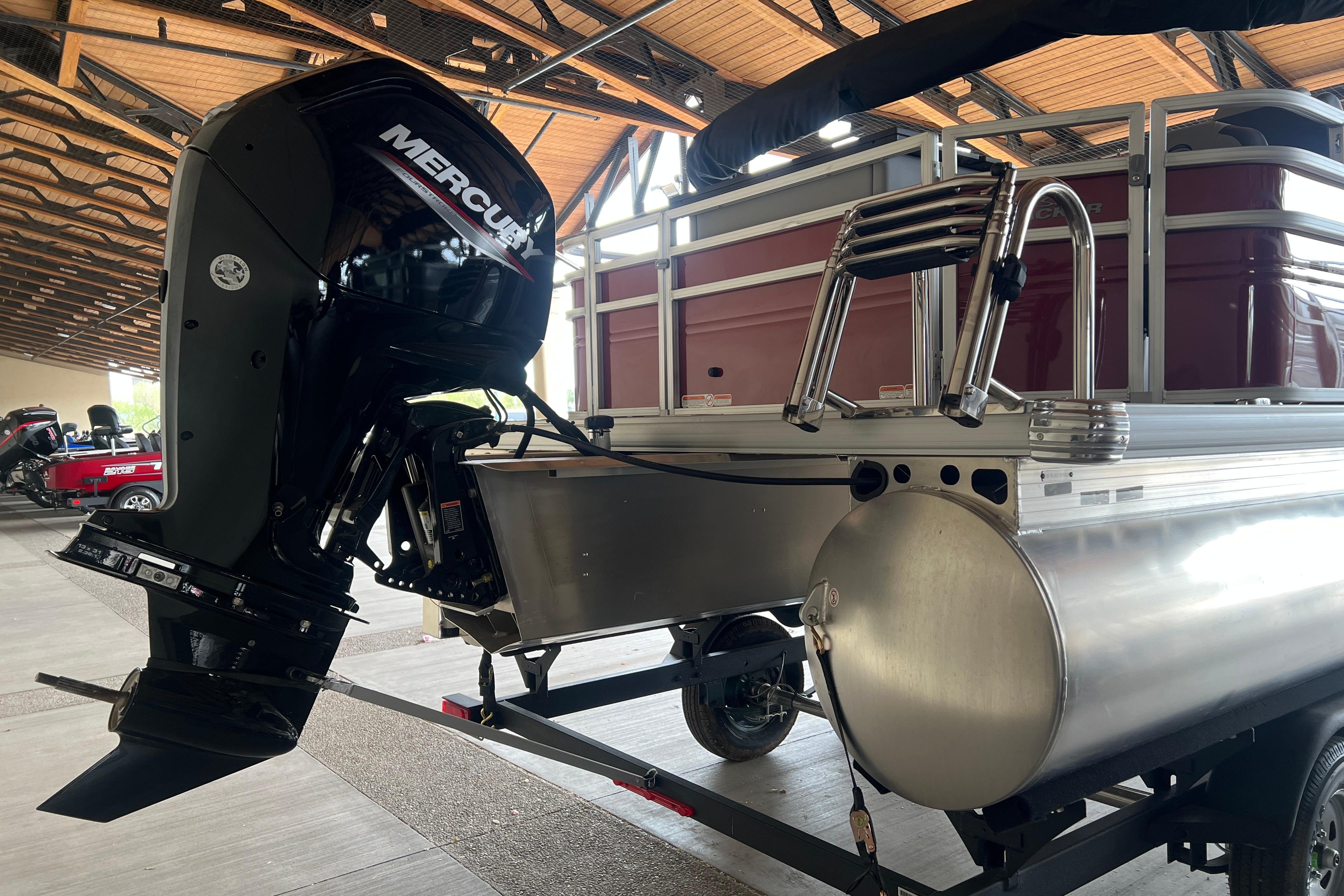 2026 Sun Tracker SportFish 20 DLX pontoon boat with Mercury outboard motor in a showroom.