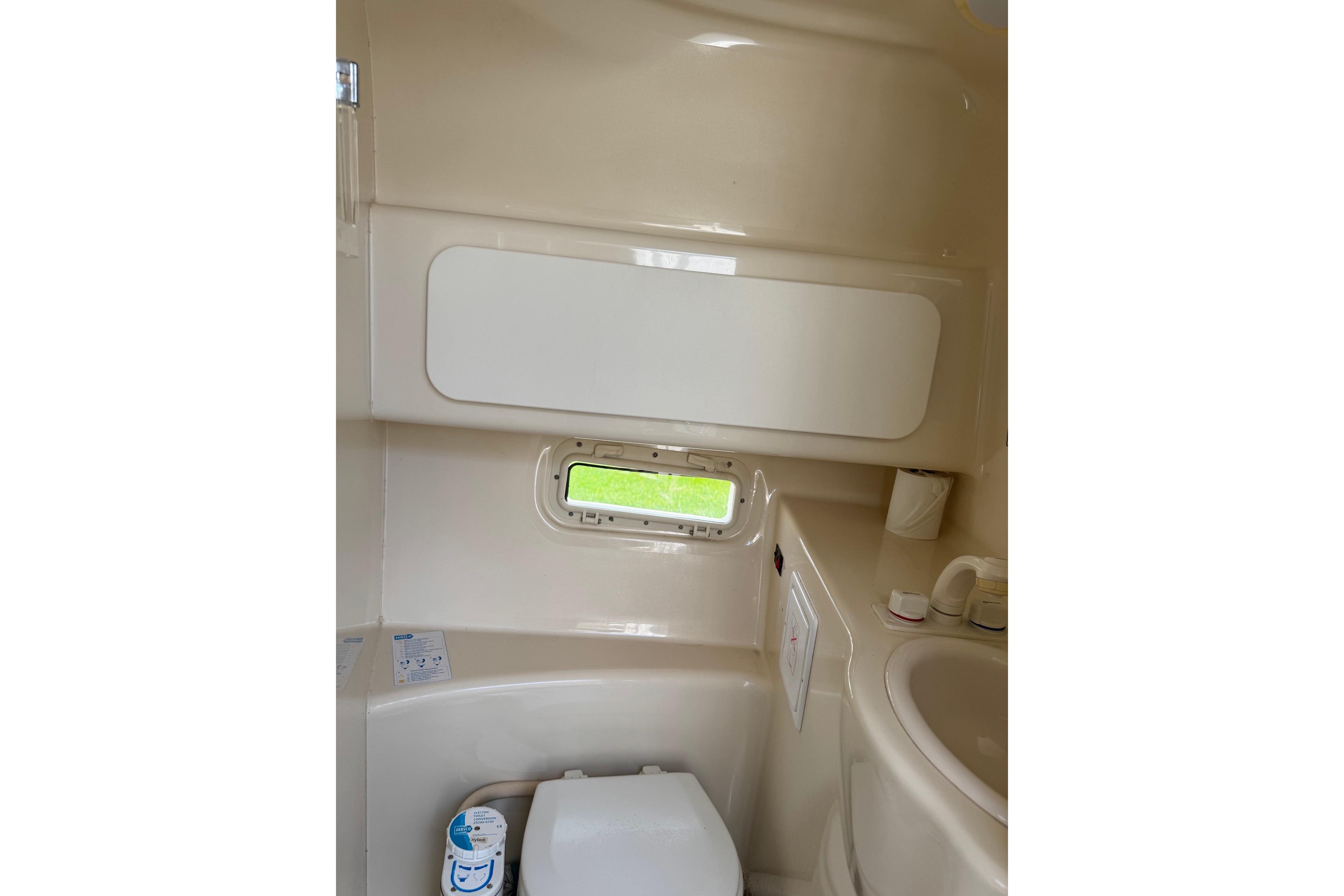 Bathroom interior of 2000 Maxum 2400 SCR boat, featuring compact design and window.