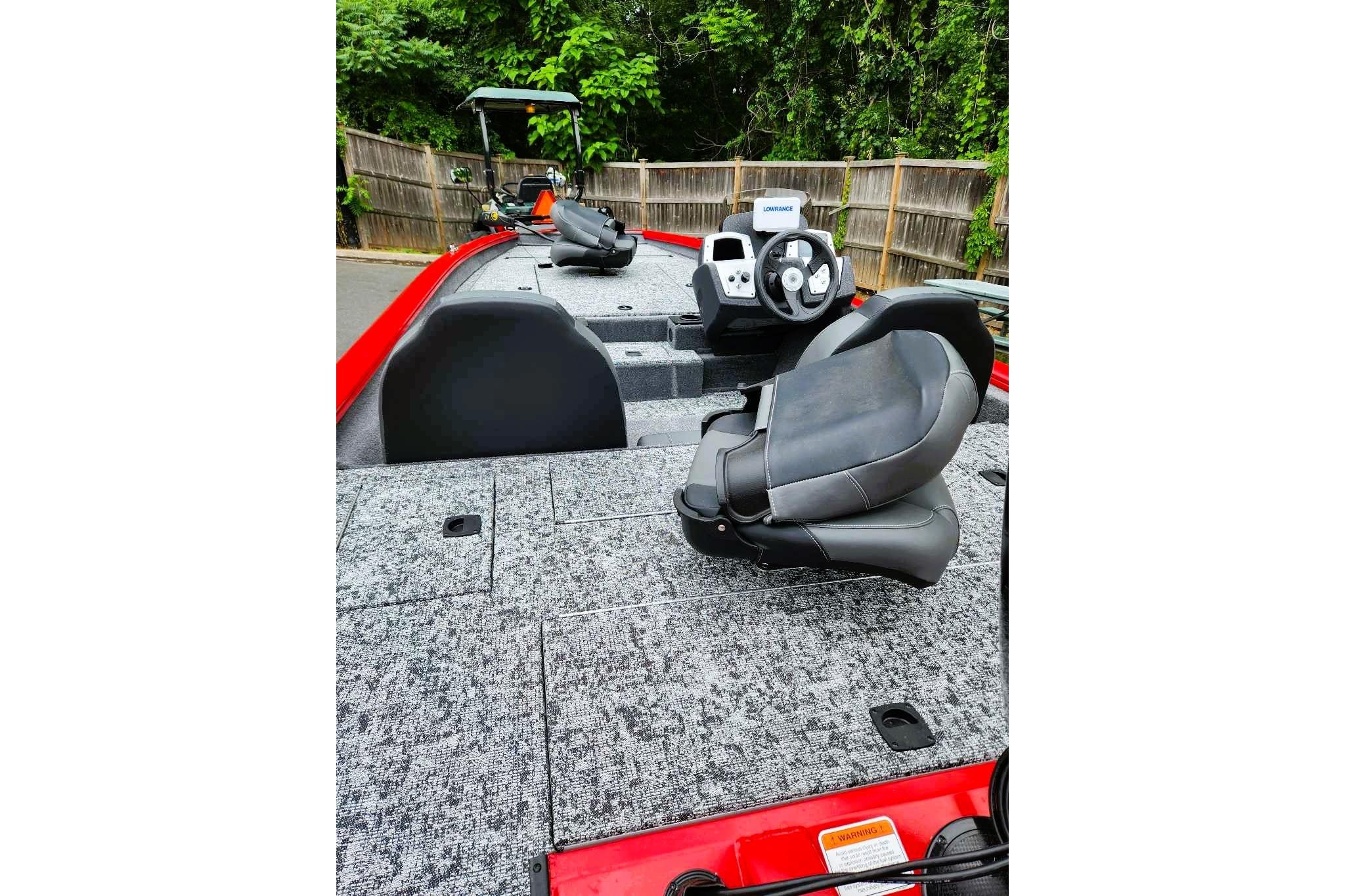 2026 Tracker Pro Team 190 boat interior with steering console and seating, surrounded by lush greenery.