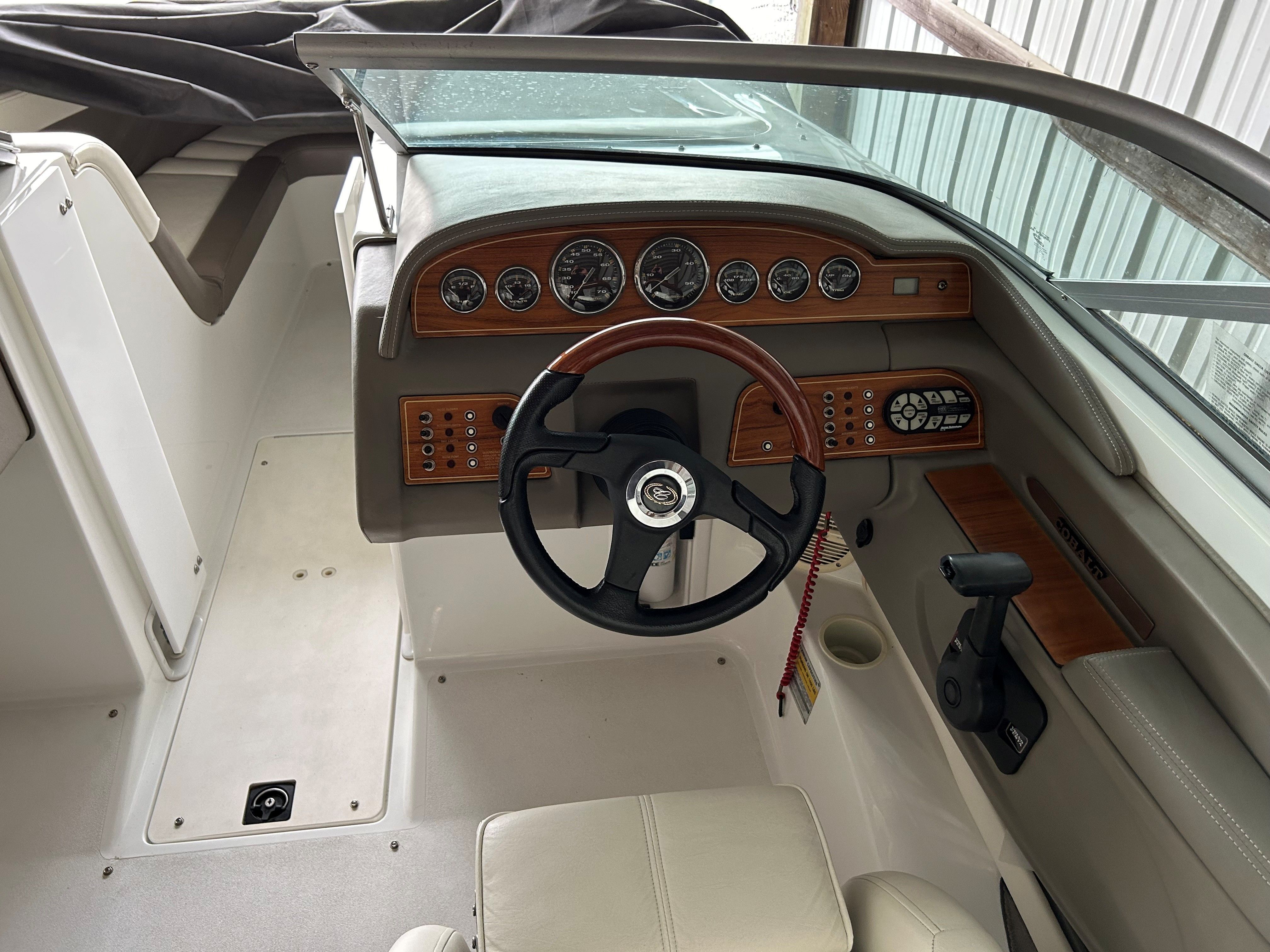 The cockpit of a Cobalt 226 boat with a wooden dashboard and steering wheel.