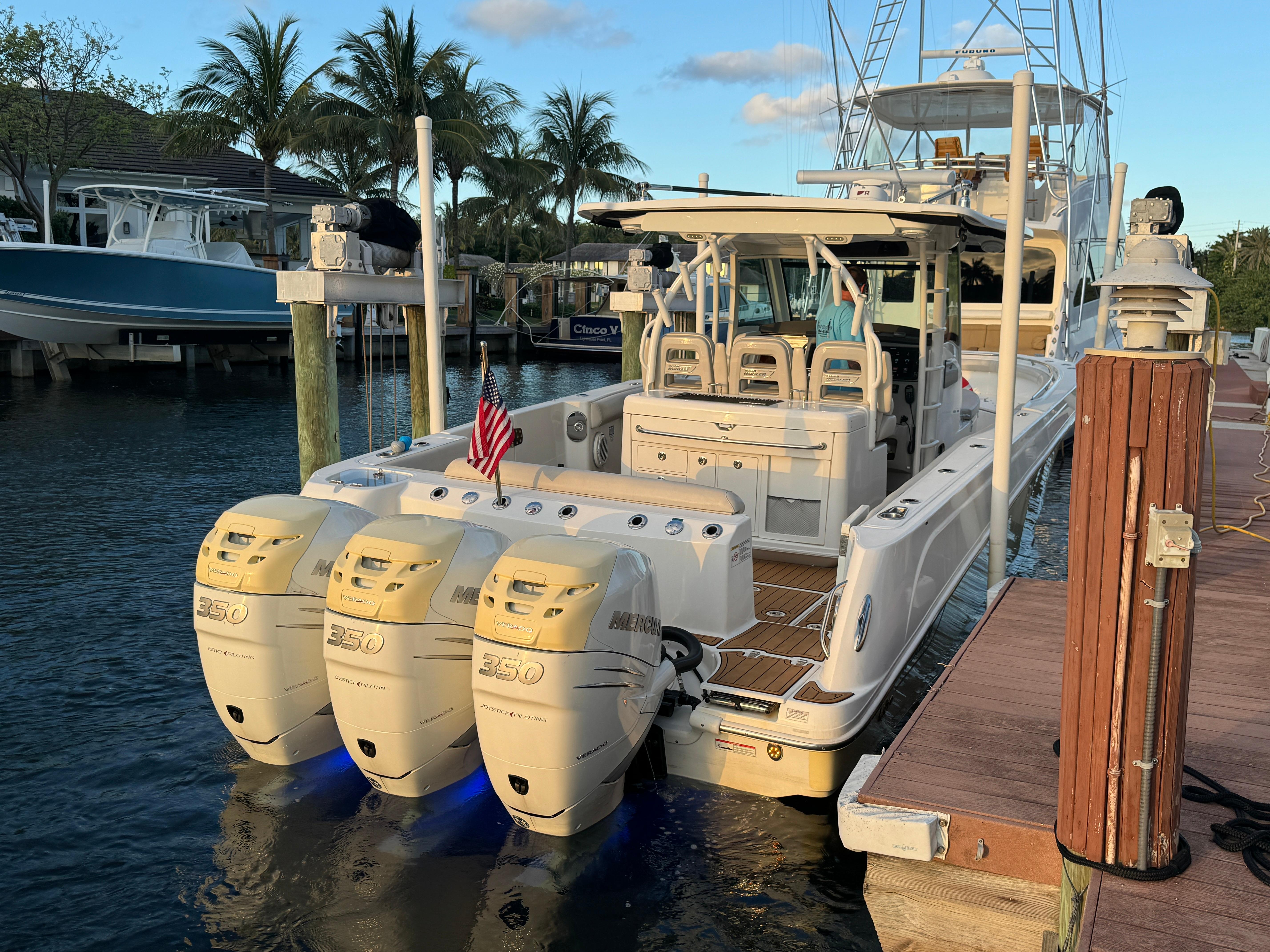 2017 Boston Whaler 370 Outrage docked, featuring triple outboard engines, palm trees in background.