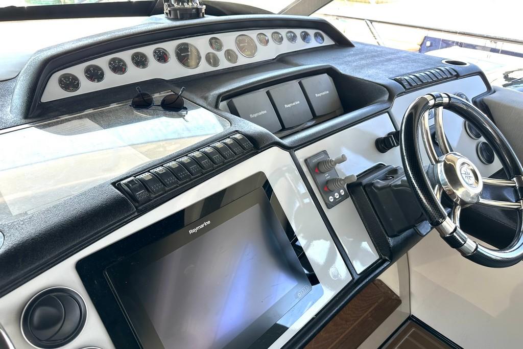 Control panel of a 2005 Princess V58 yacht with steering wheel and navigation equipment.