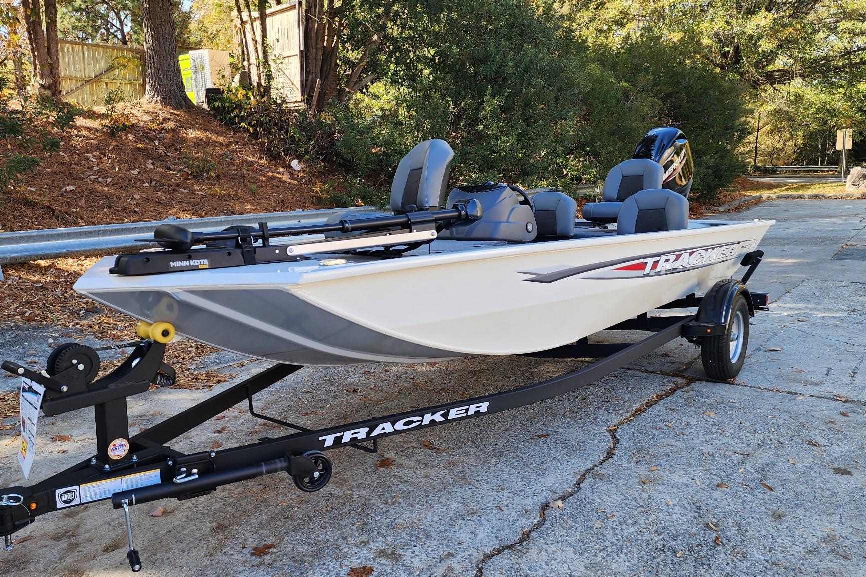 2026 Tracker Pro 170 boat on trailer, parked outdoors, surrounded by trees.