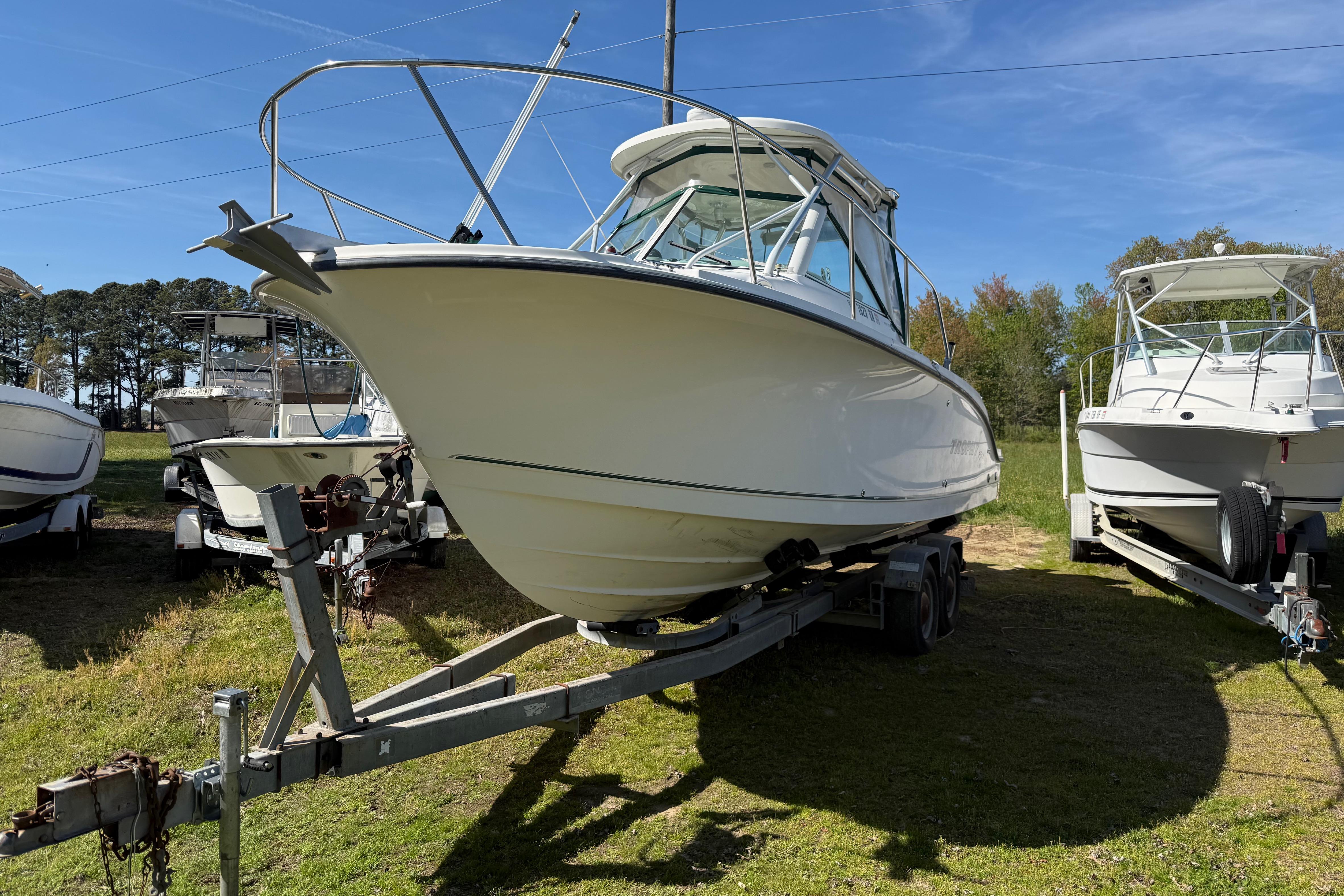 2006 Trophy 2502 Walkaround boat on trailer, parked outdoors under clear blue sky.