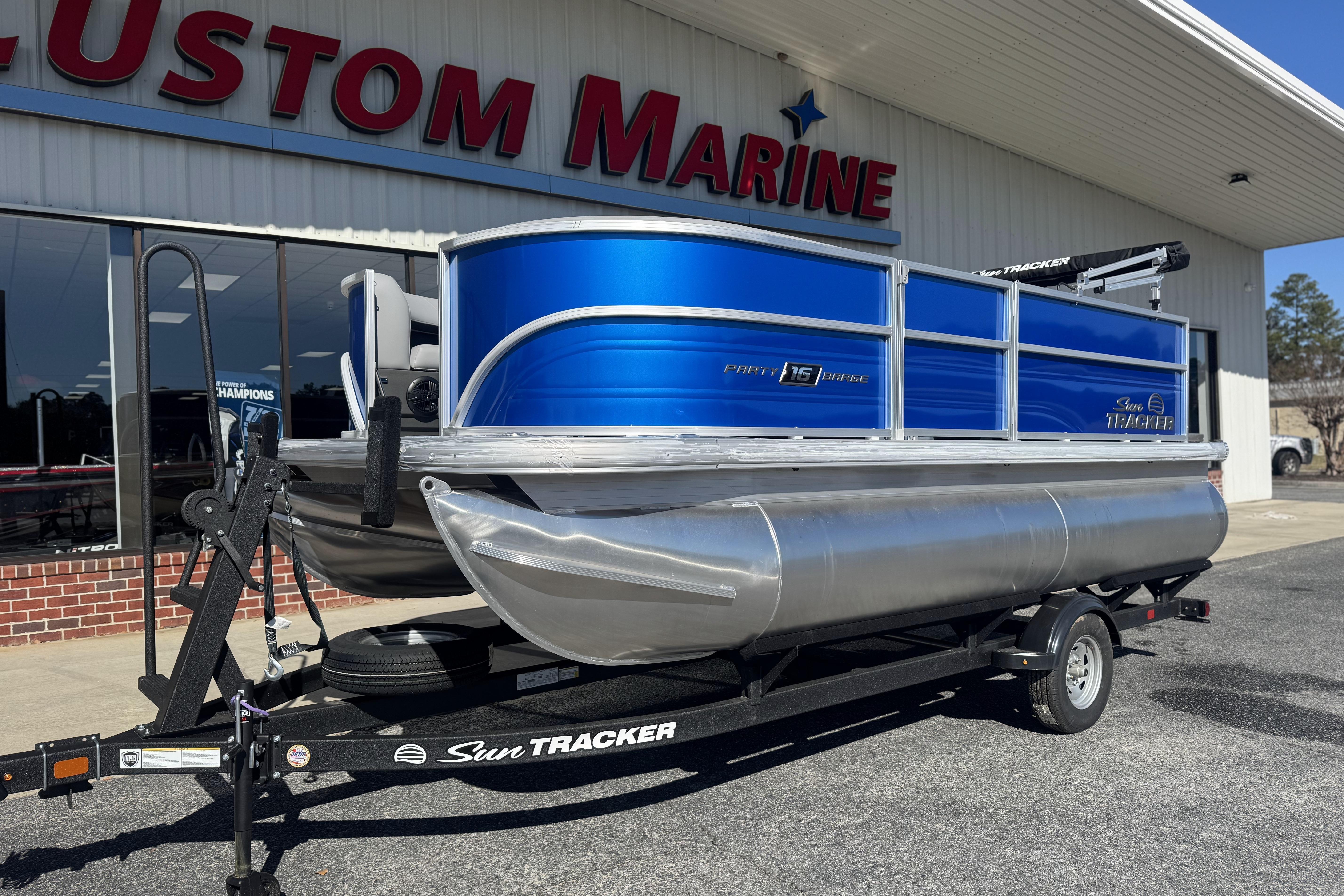 2026 Sun Tracker Party Barge 16 DLX pontoon boat on trailer outside Custom Marine.
