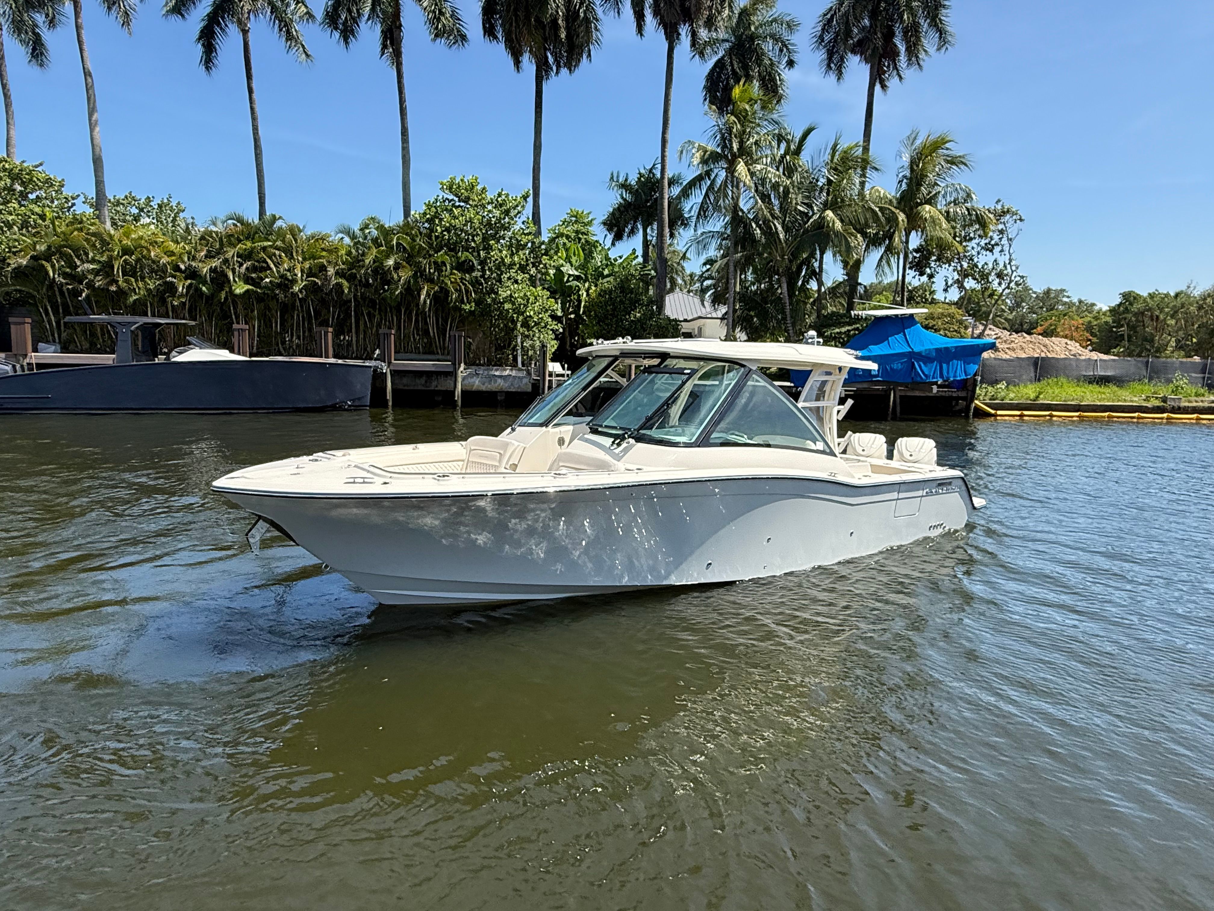 2027 Grady-White Freedom 325 on calm water, surrounded by palm trees and a dock.