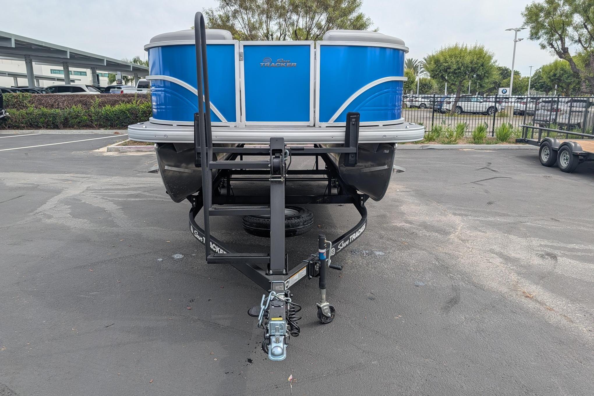 2026 Sun Tracker Party Barge 20 DLX pontoon boat on trailer in parking lot.