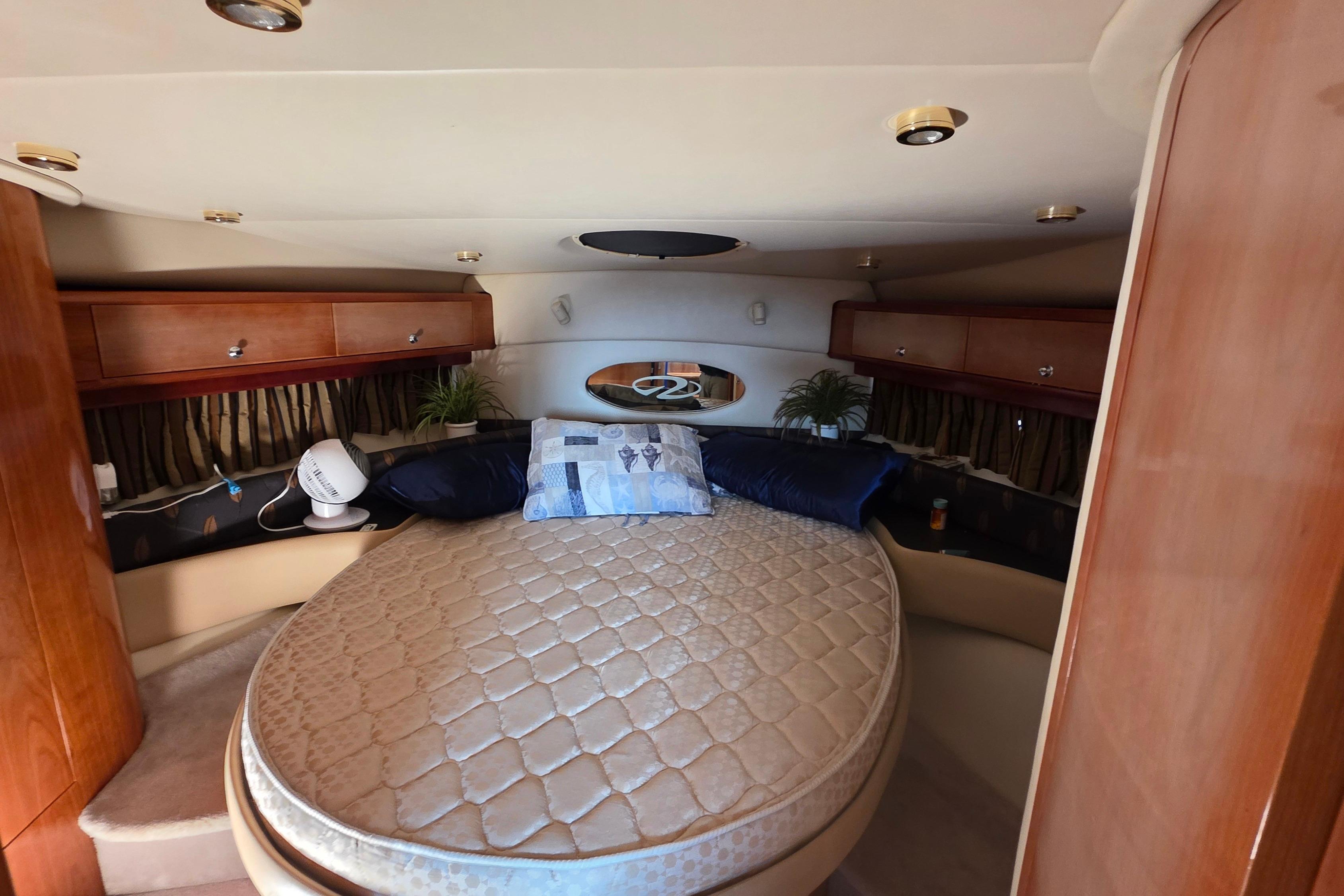 Luxurious cabin interior of 2002 Regal Commodore 4260 yacht with cozy bed and wooden accents.