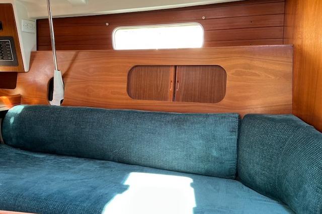 Interior of 2000 Beneteau Oceanis 321 sailboat with blue sofa and wooden paneling.
