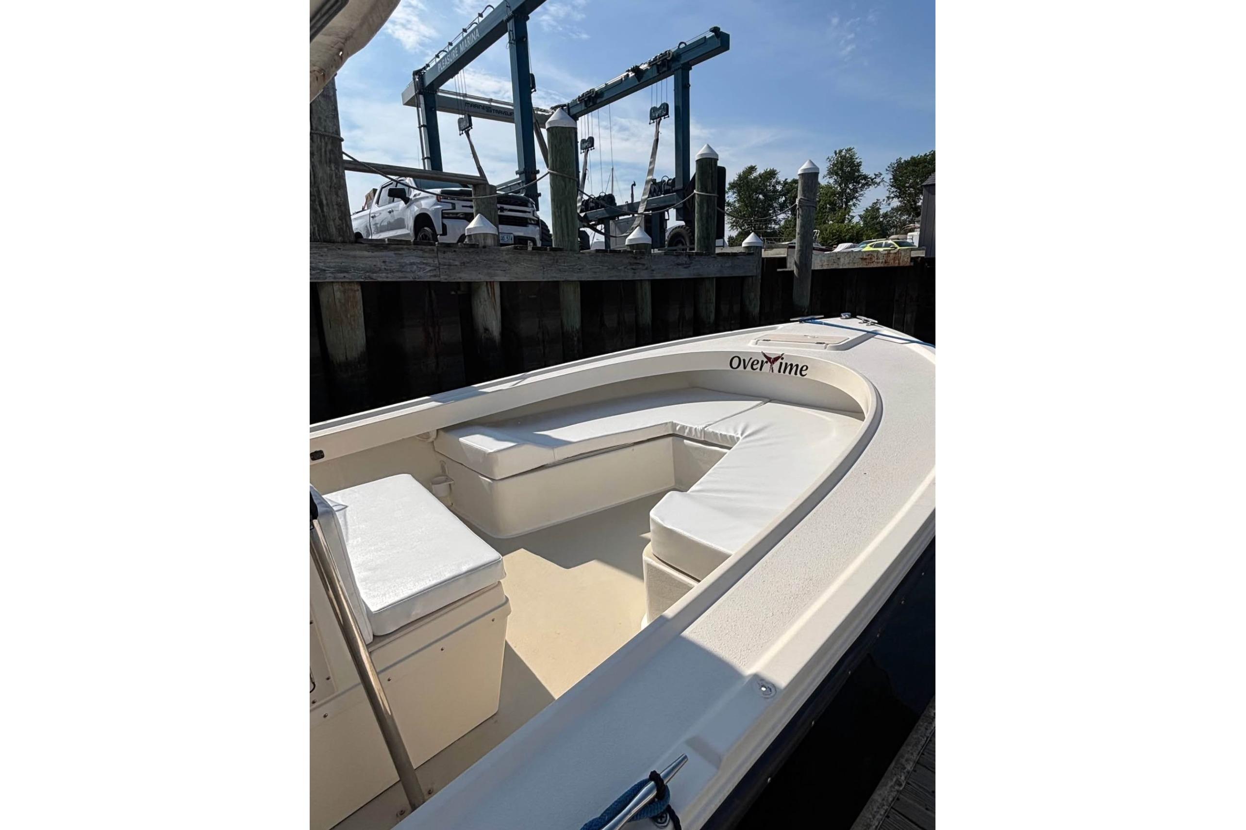 1999 Parker 2501 Center Console boat docked, featuring cushioned seating and "Over Time" name.