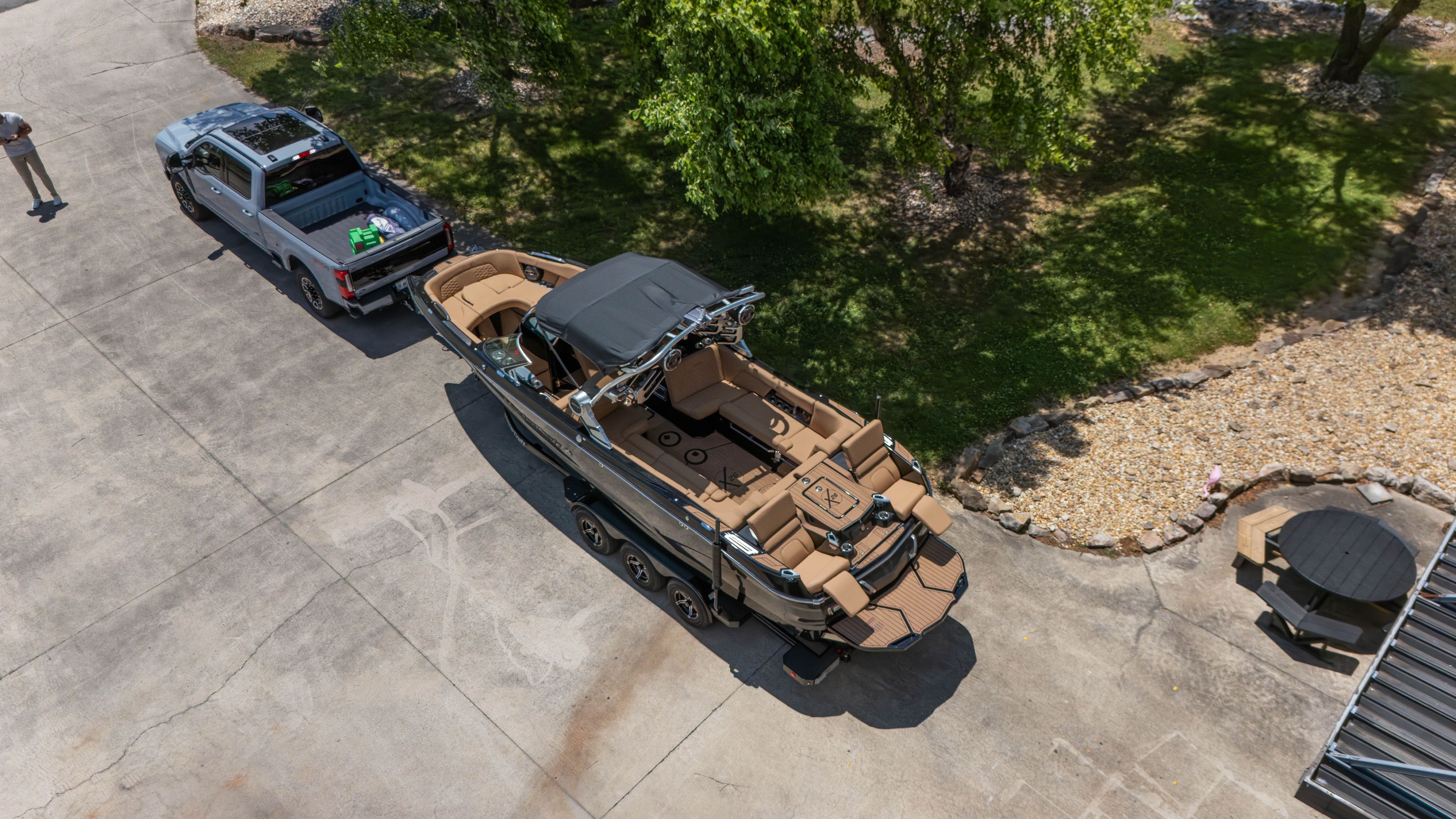 Aerial view of a MasterCraft X26 boat on a trailer, towed by a pickup truck.