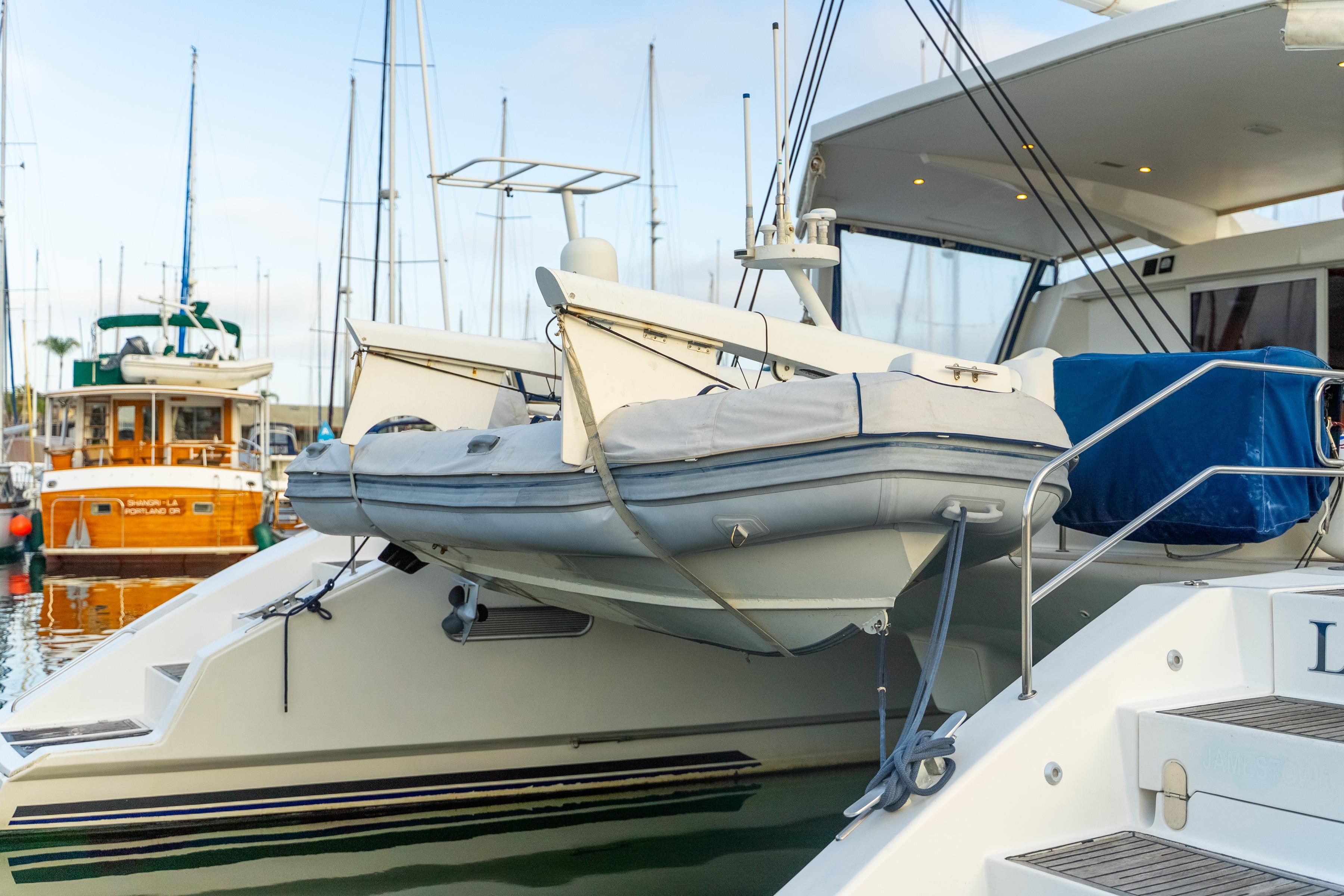 Catana 65 yacht from 2009 with a dinghy on the stern, docked at a marina.