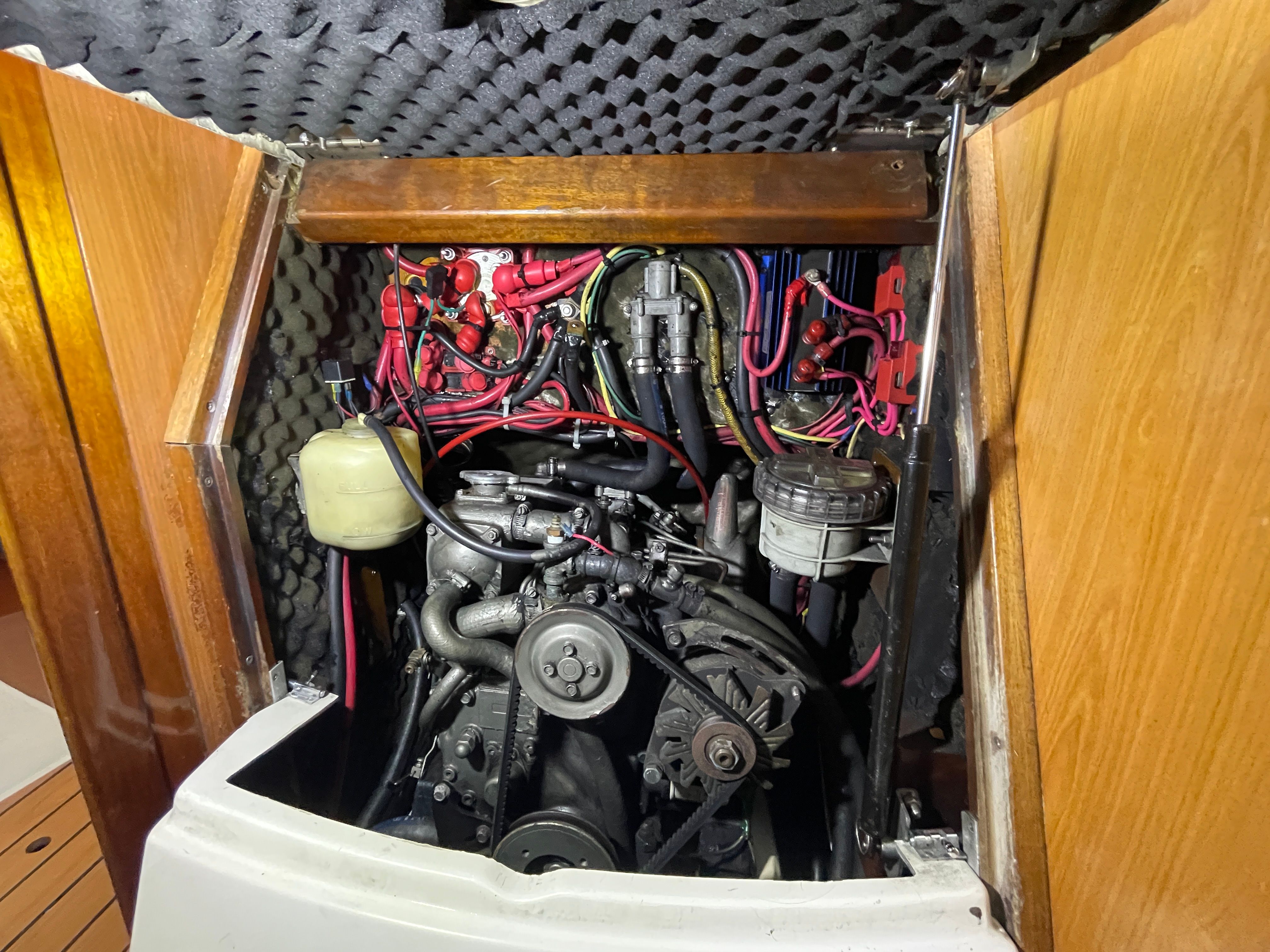 The engine compartment of a 2000 Beneteau Oceanis 361 shows a well-maintained engine with hoses and wires.