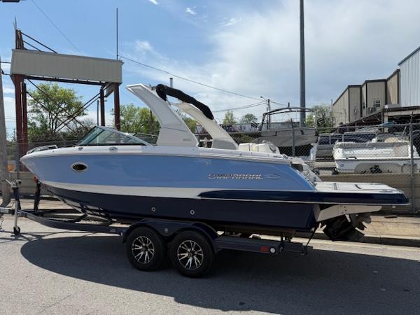 2023 Chaparral 267 SSX boat on trailer, blue and white design, parked outdoors.