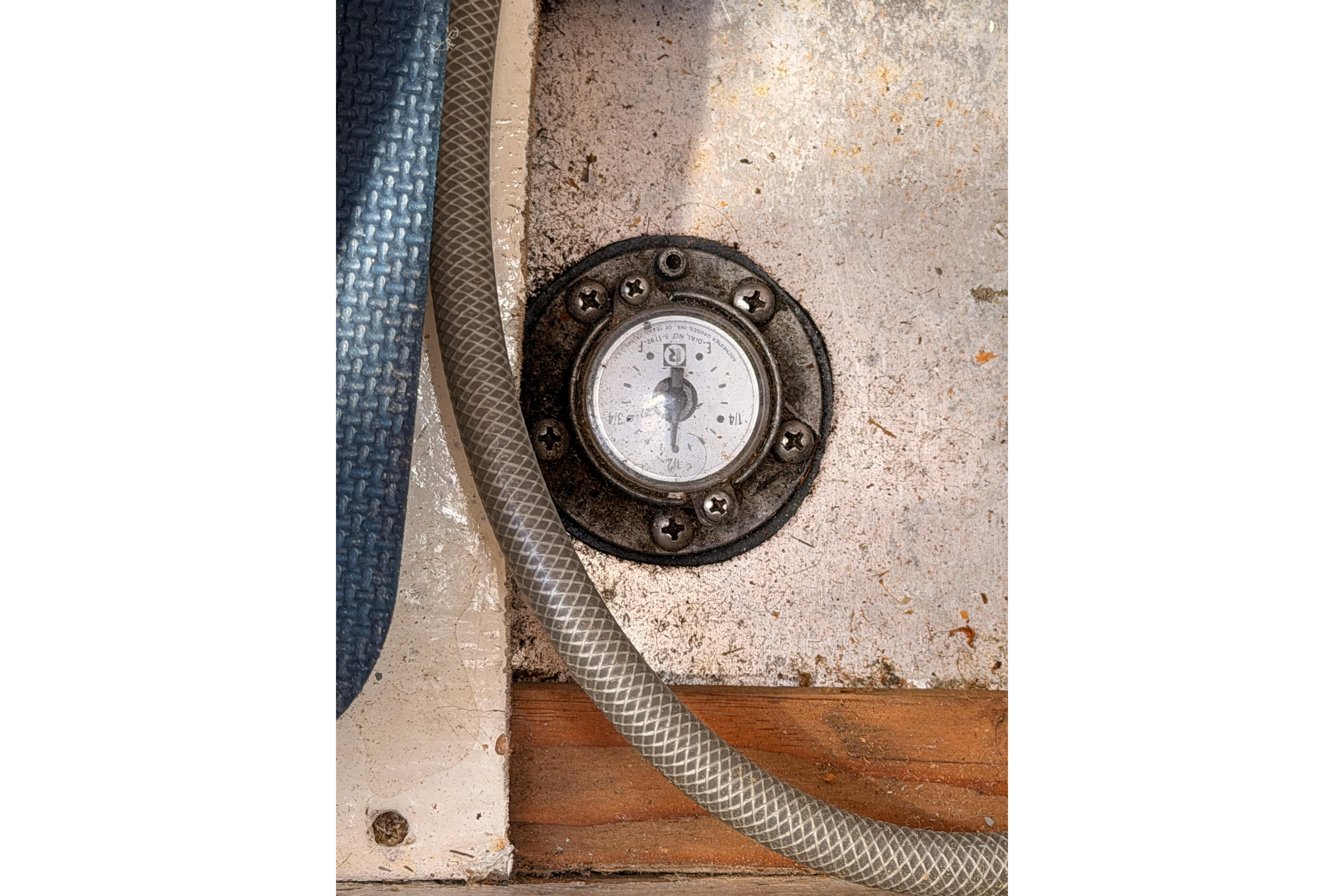 Fuel gauge on a 1991 Caliber 33 boat, surrounded by hoses and textured surfaces.