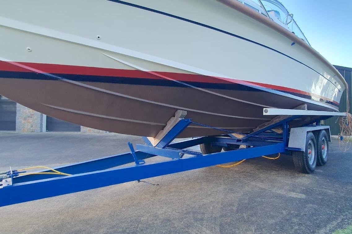 1989 Fairey Spearfish MKIII boat on a blue trailer, side view.