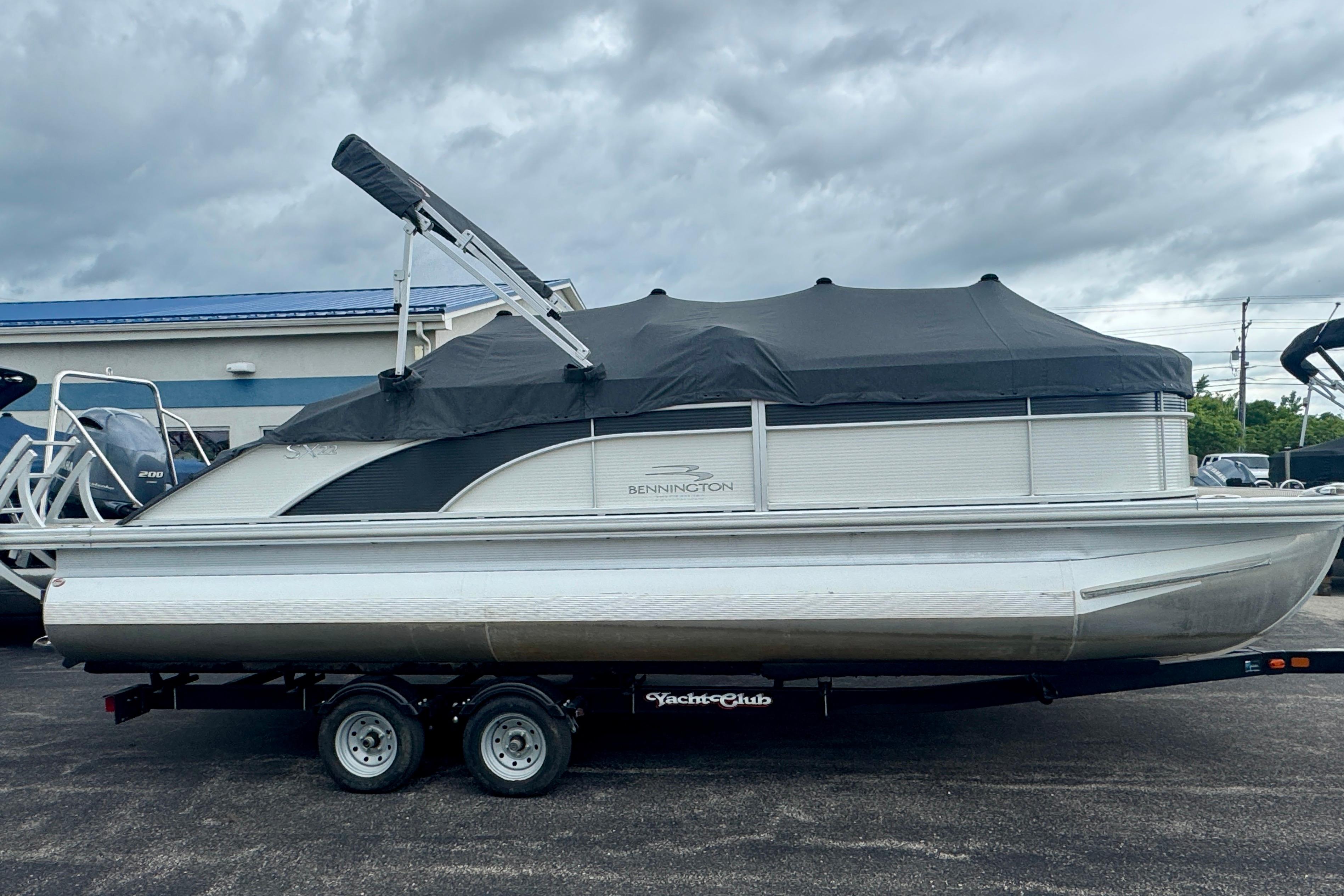 2019 Bennington SX 22 SSBXP pontoon boat on trailer, covered, under cloudy sky.