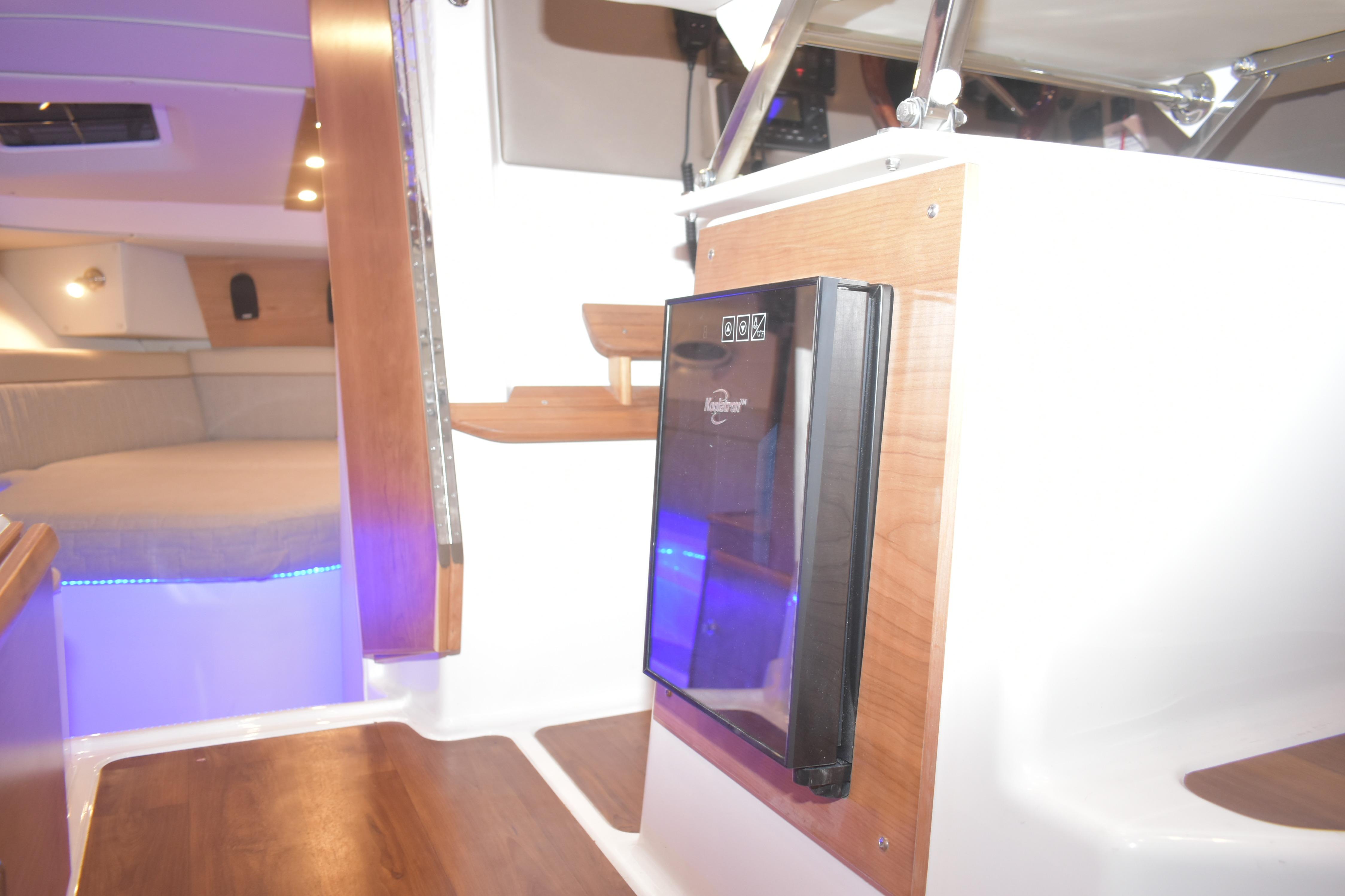 2026 Cutwater C-32 CB interior with wood accents and compact refrigerator.