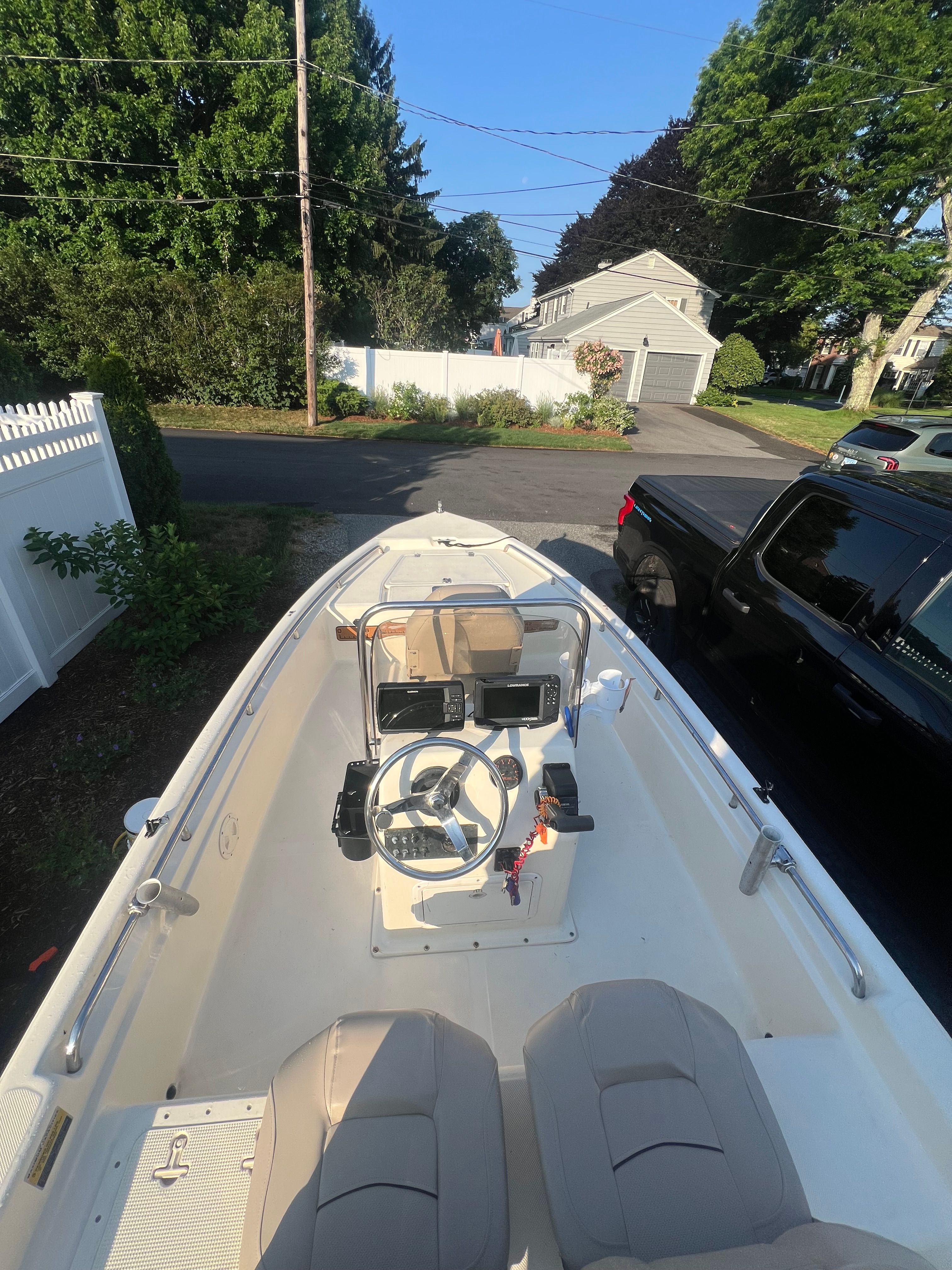 A 2001 Scout 151 Sportfish boat is parked in a driveway. It features an open cockpit with a helm and beige seats.