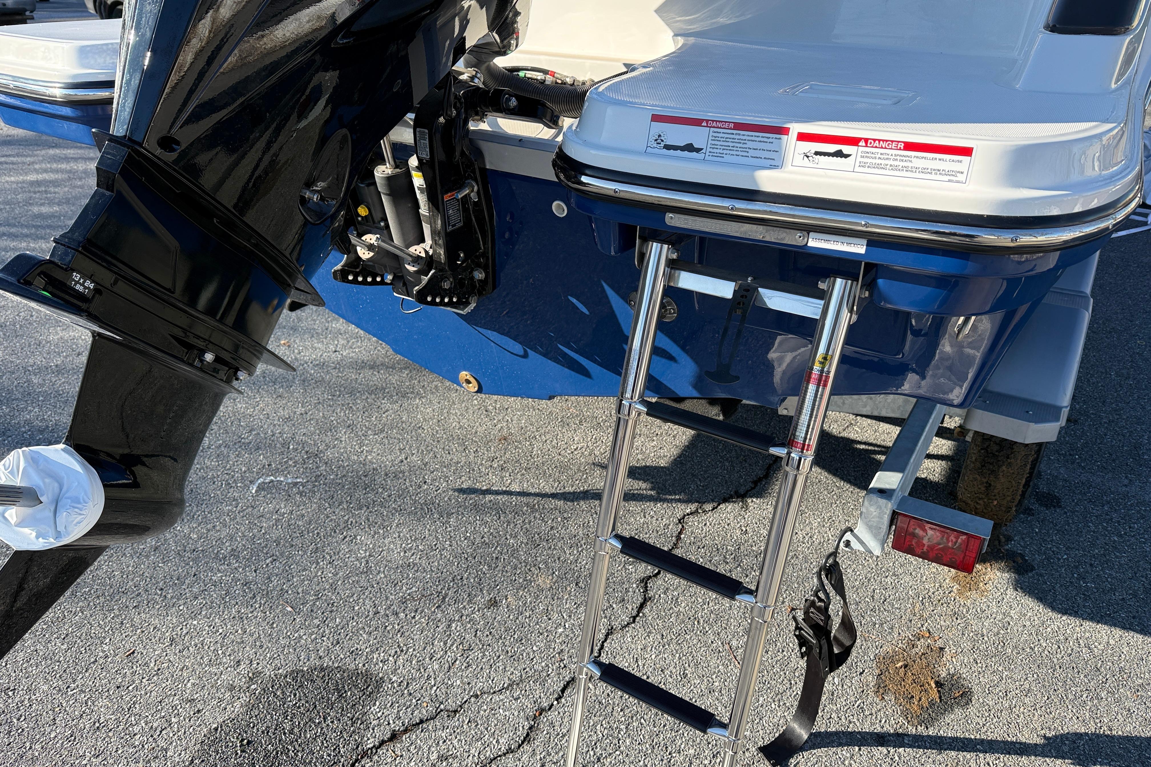 Bayliner Trophy T22CC 2026 boat with ladder and outboard motor on a trailer.
