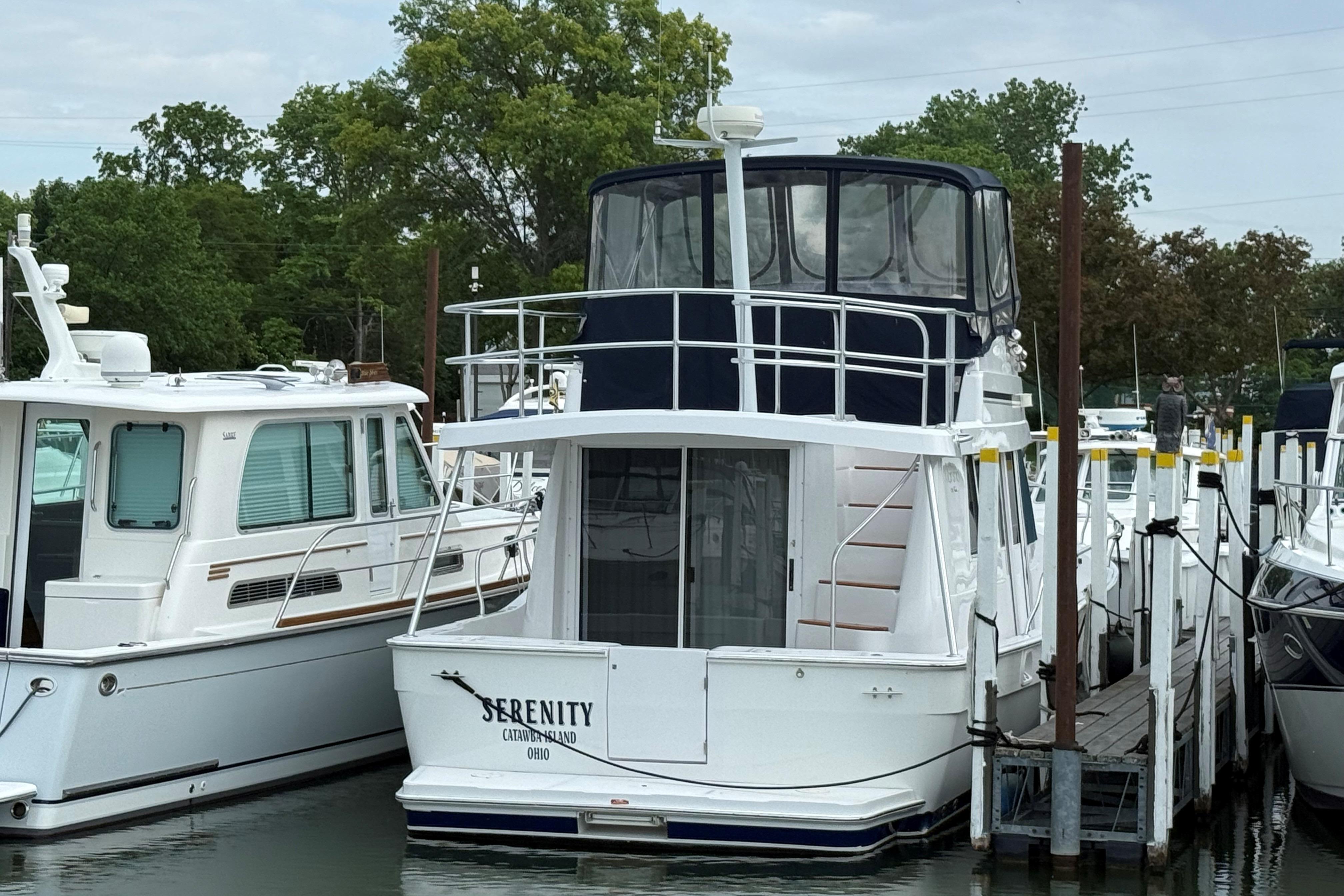 1999 Mainship 350 Trawler docked, featuring "Serenity" name, surrounded by other boats.