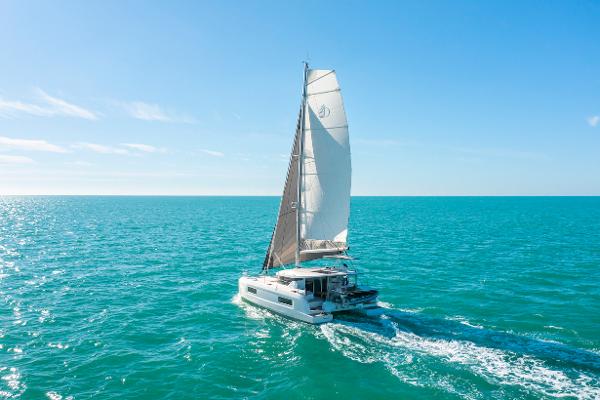 2025 Lagoon 38 catamaran sailing on clear blue ocean under sunny skies.