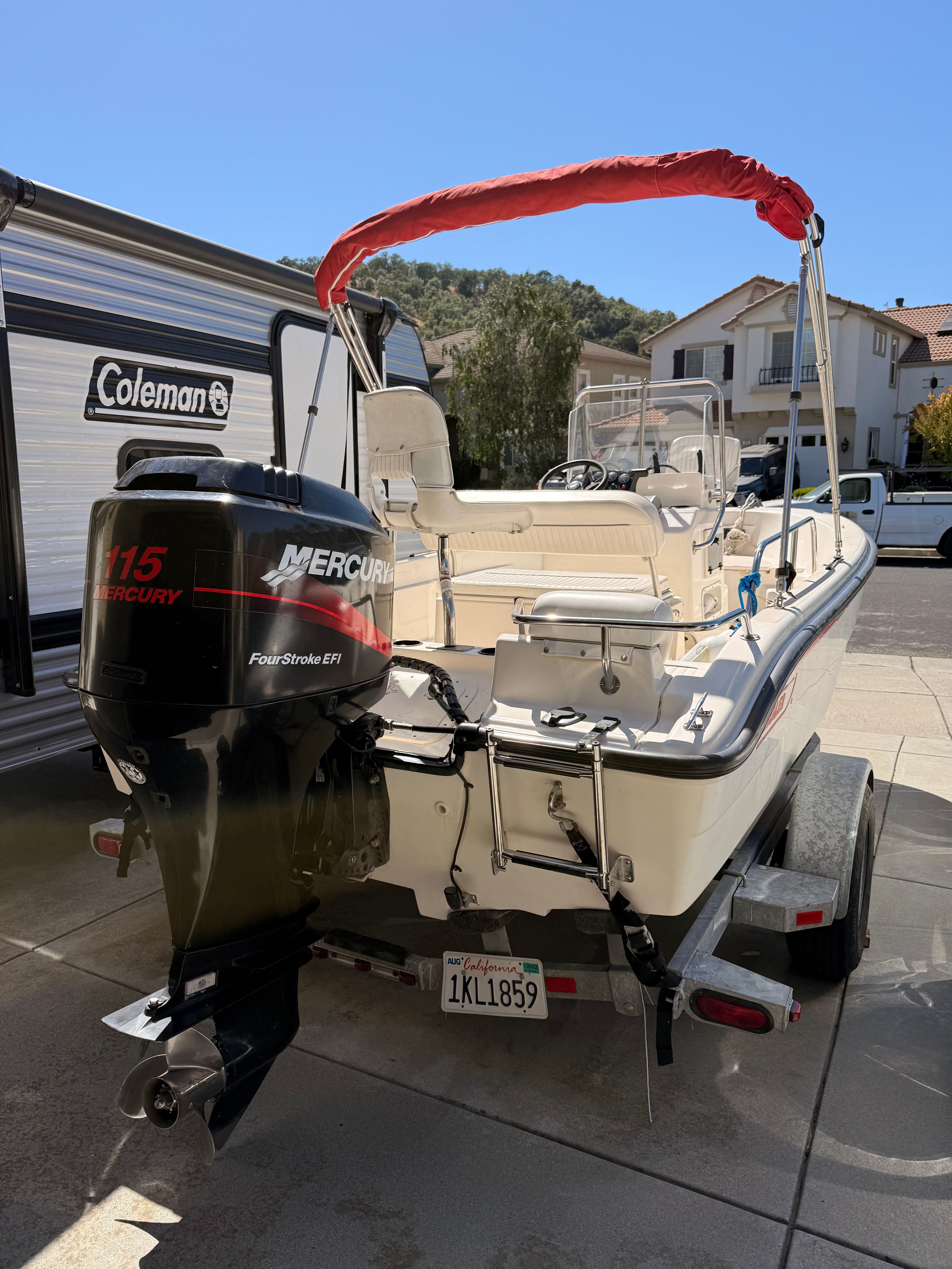 A 2002 Boston Whaler 160 Dauntless on a trailer in a driveway.