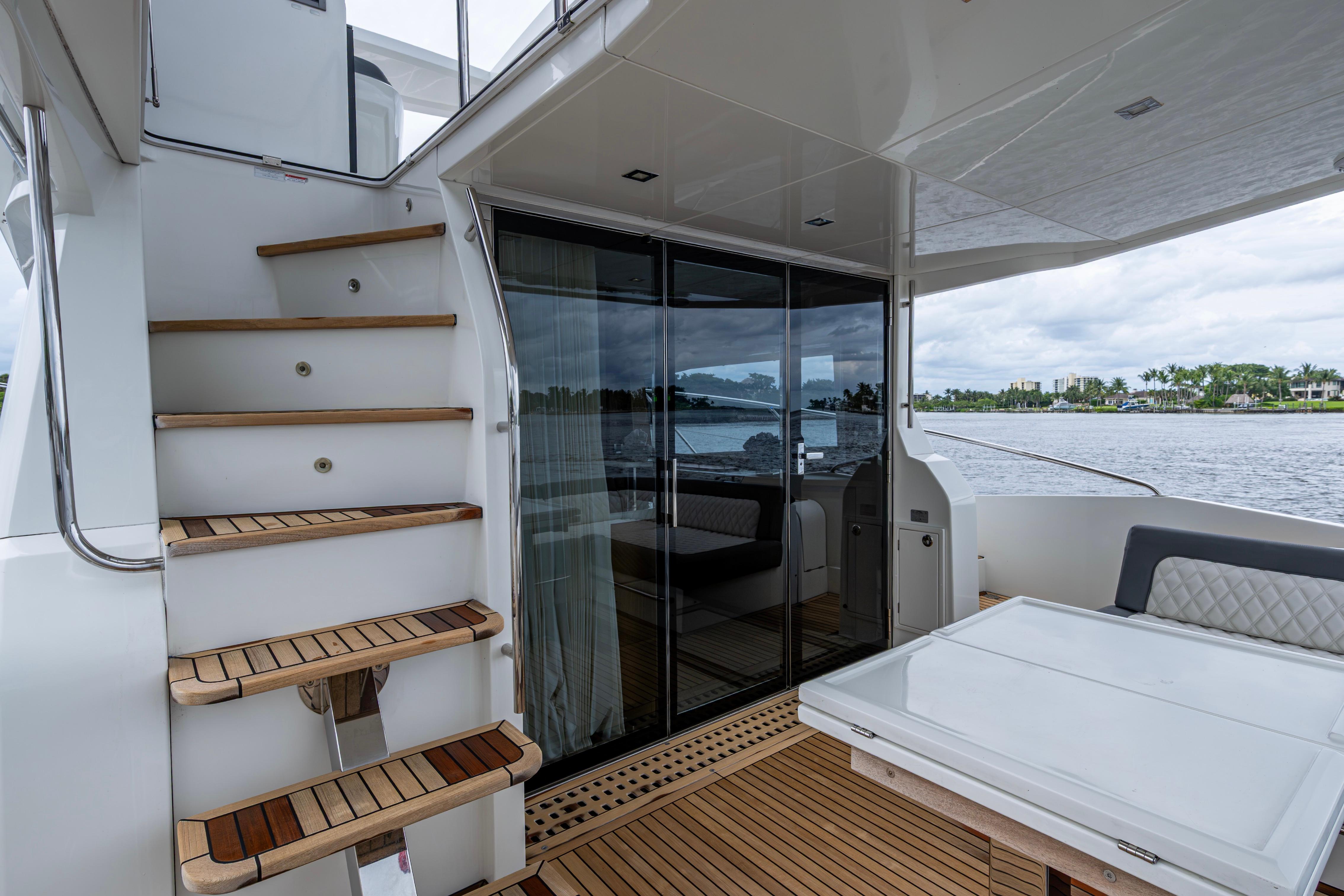 2020 Galeon 550 Fly yacht interior with wooden stairs and glass doors, overlooking water.