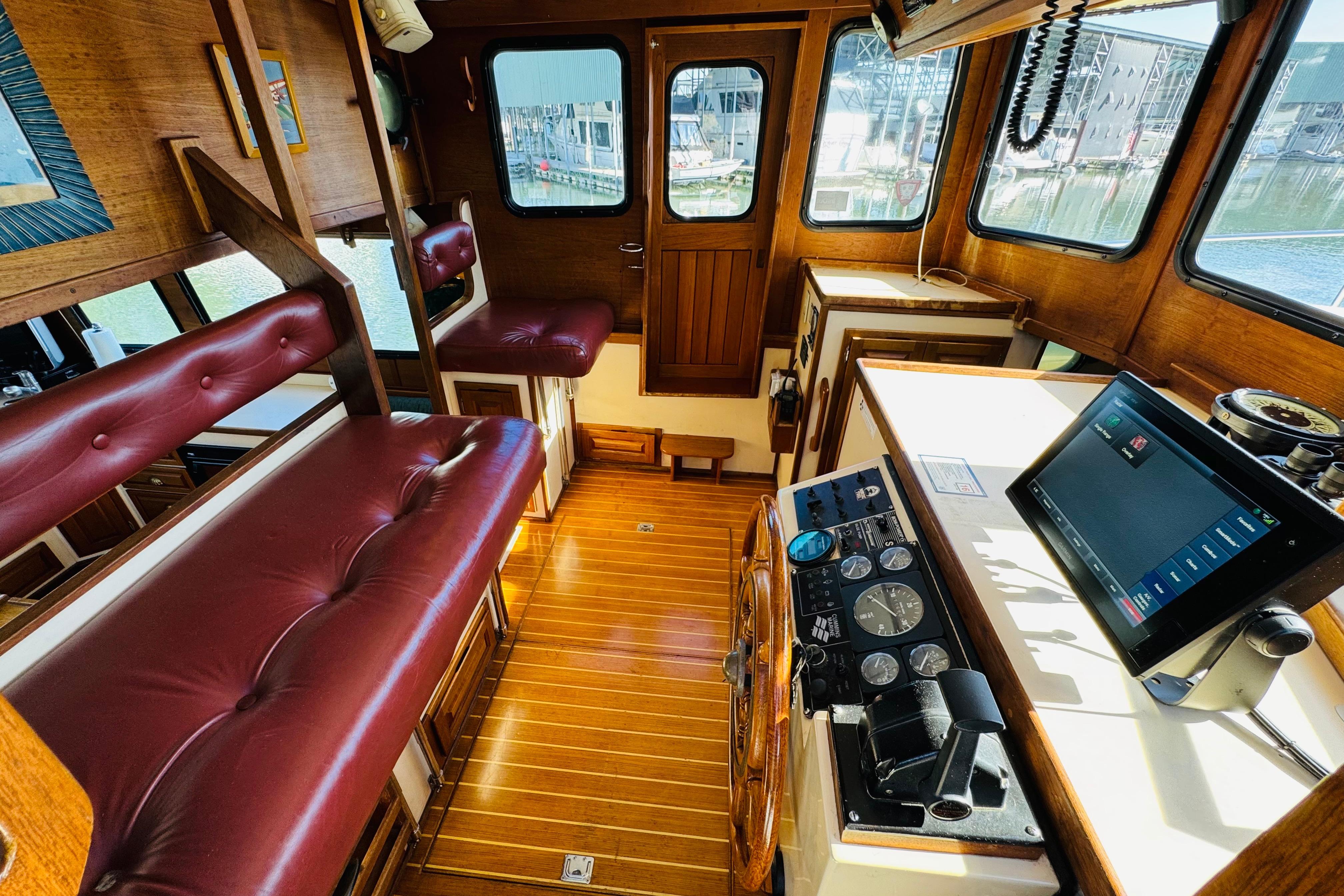 Interior of a 1996 Nordic Tug 32 with wood paneling and red leather seating.