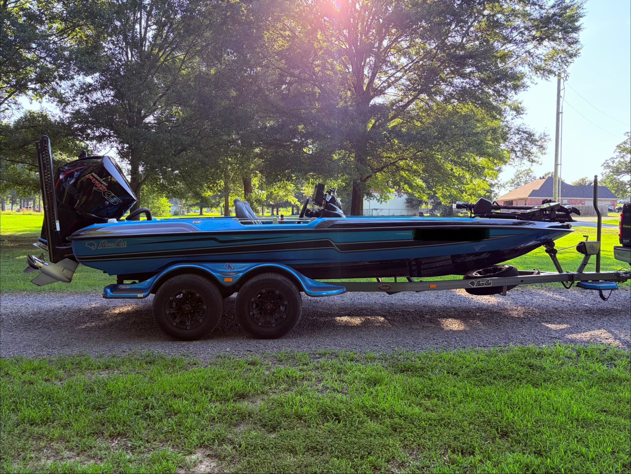 A 2023 Bass Cat Cougar FTD on a trailer, surrounded by trees and grass.