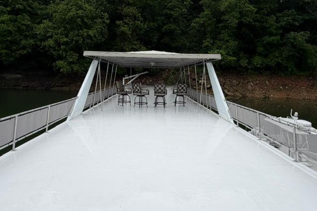 Spacious deck of 1997 Stardust Houseboat 18x83 with chairs, surrounded by lush greenery.