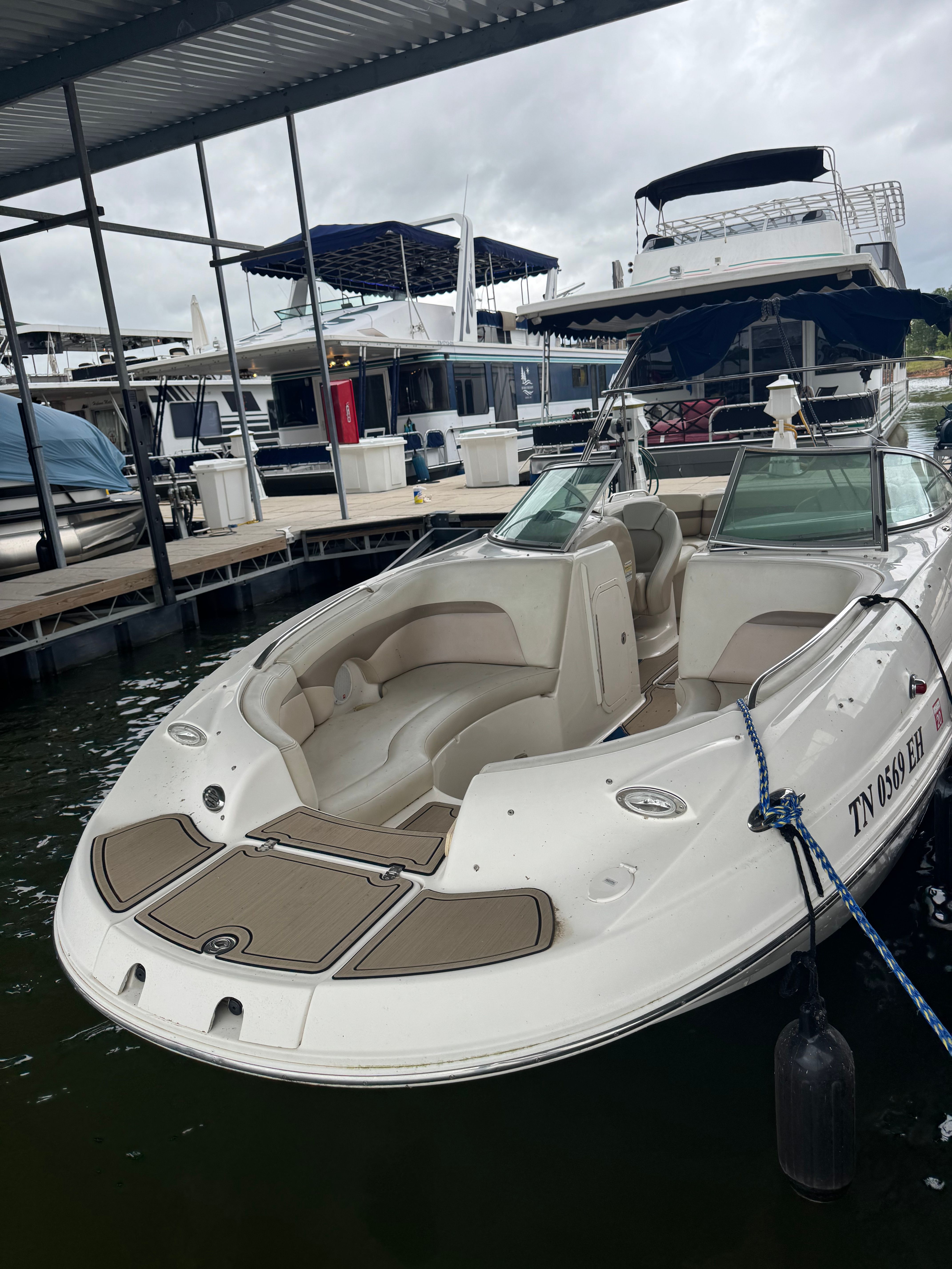 A white Chaparral Sunesta 223 boat docked in a marina, surrounded by other boats.