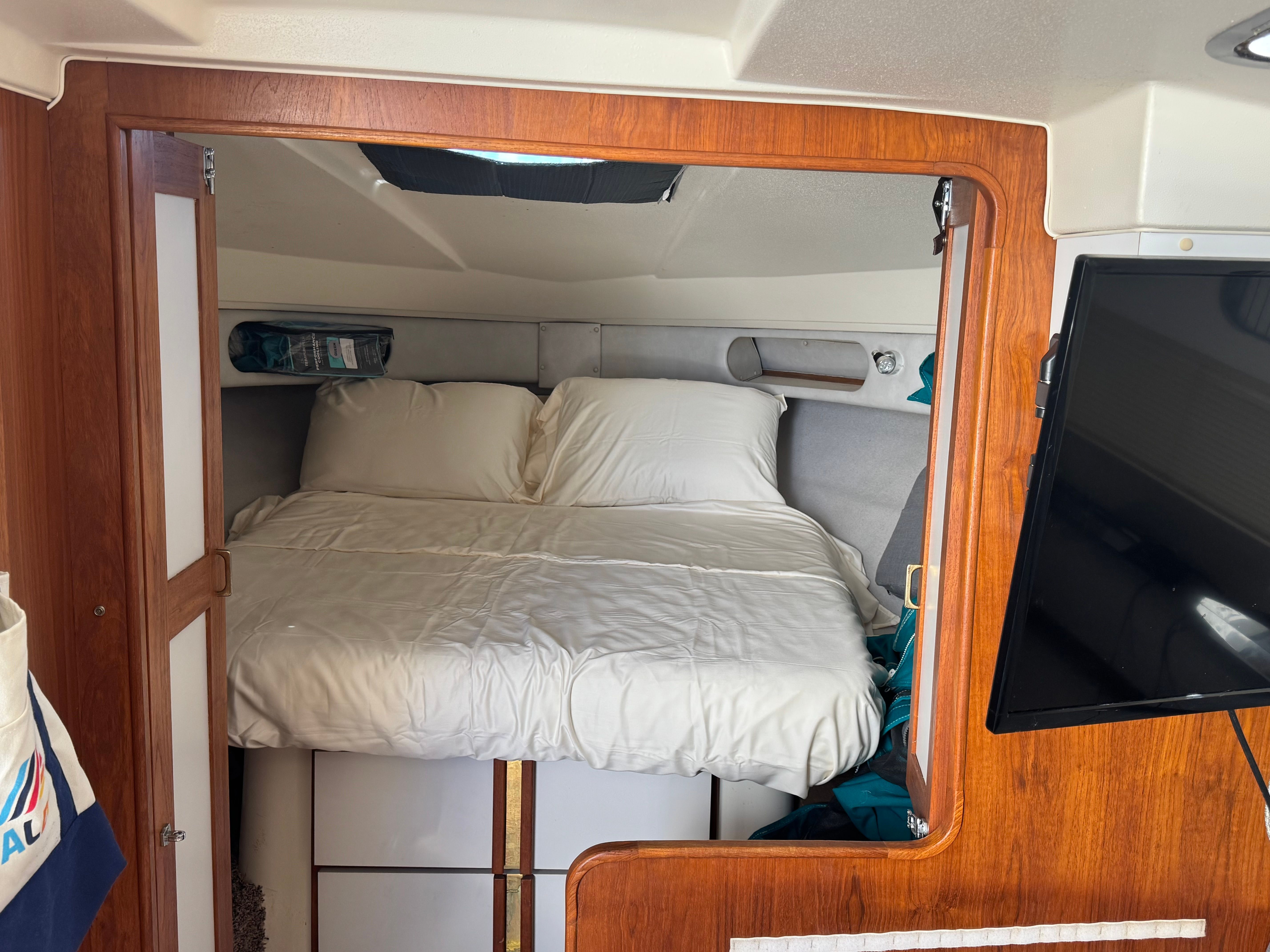 The image shows a cozy cabin with a double bed and a TV mounted on the wall.