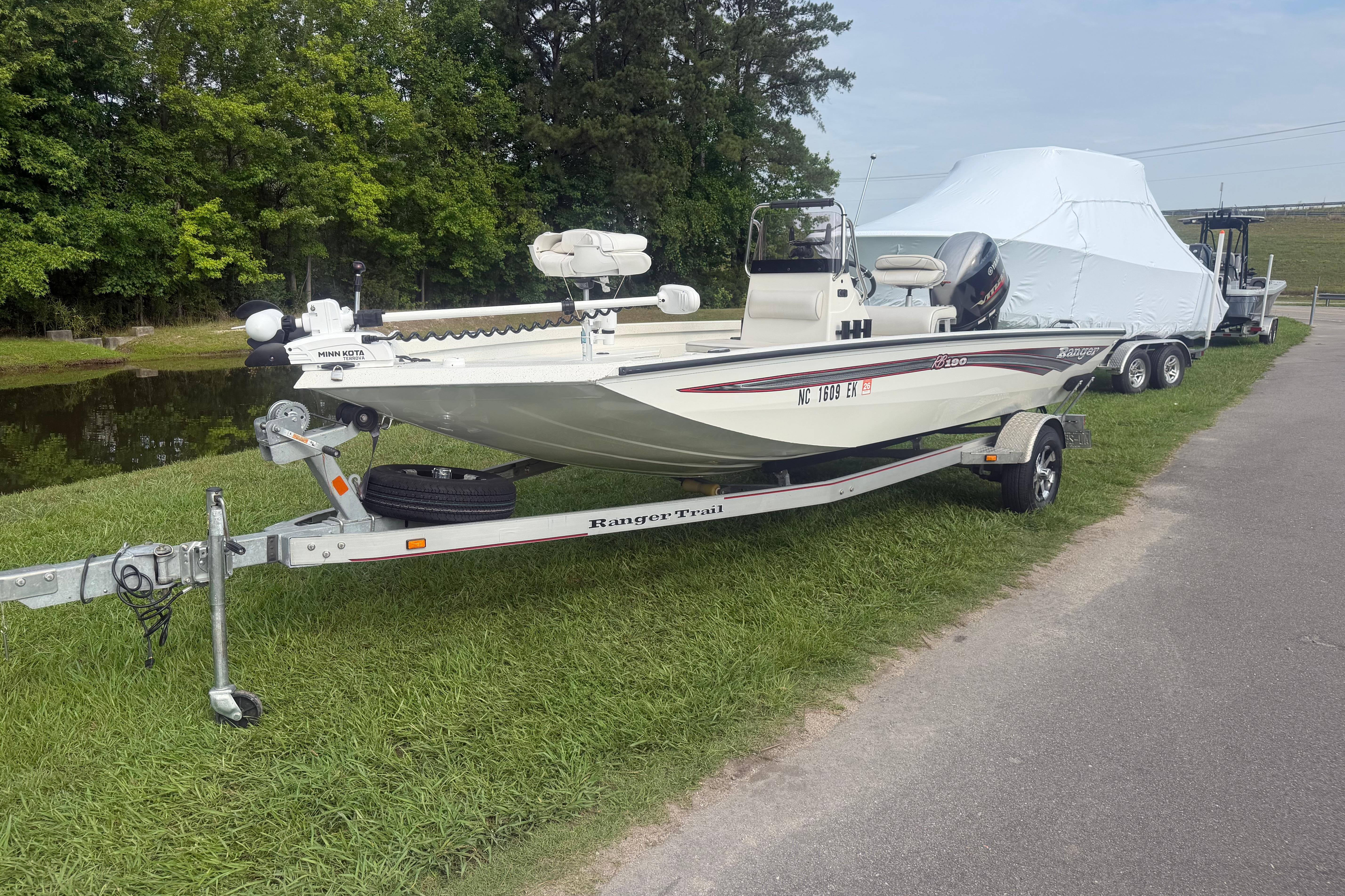 2018 Ranger RB190 boat on trailer, parked on grass beside a pond.