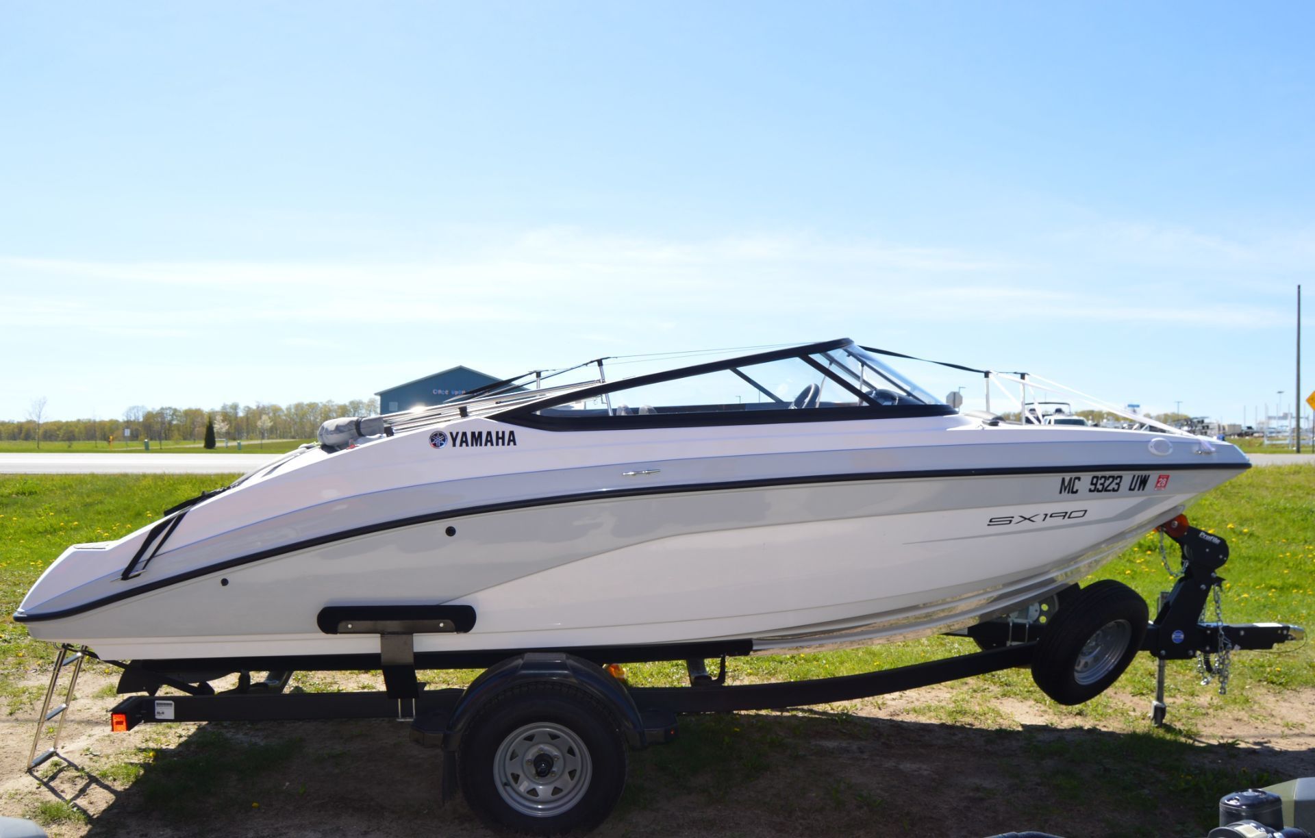 A 2023 Yamaha SX190 boat on a trailer, set on a grassy area.
