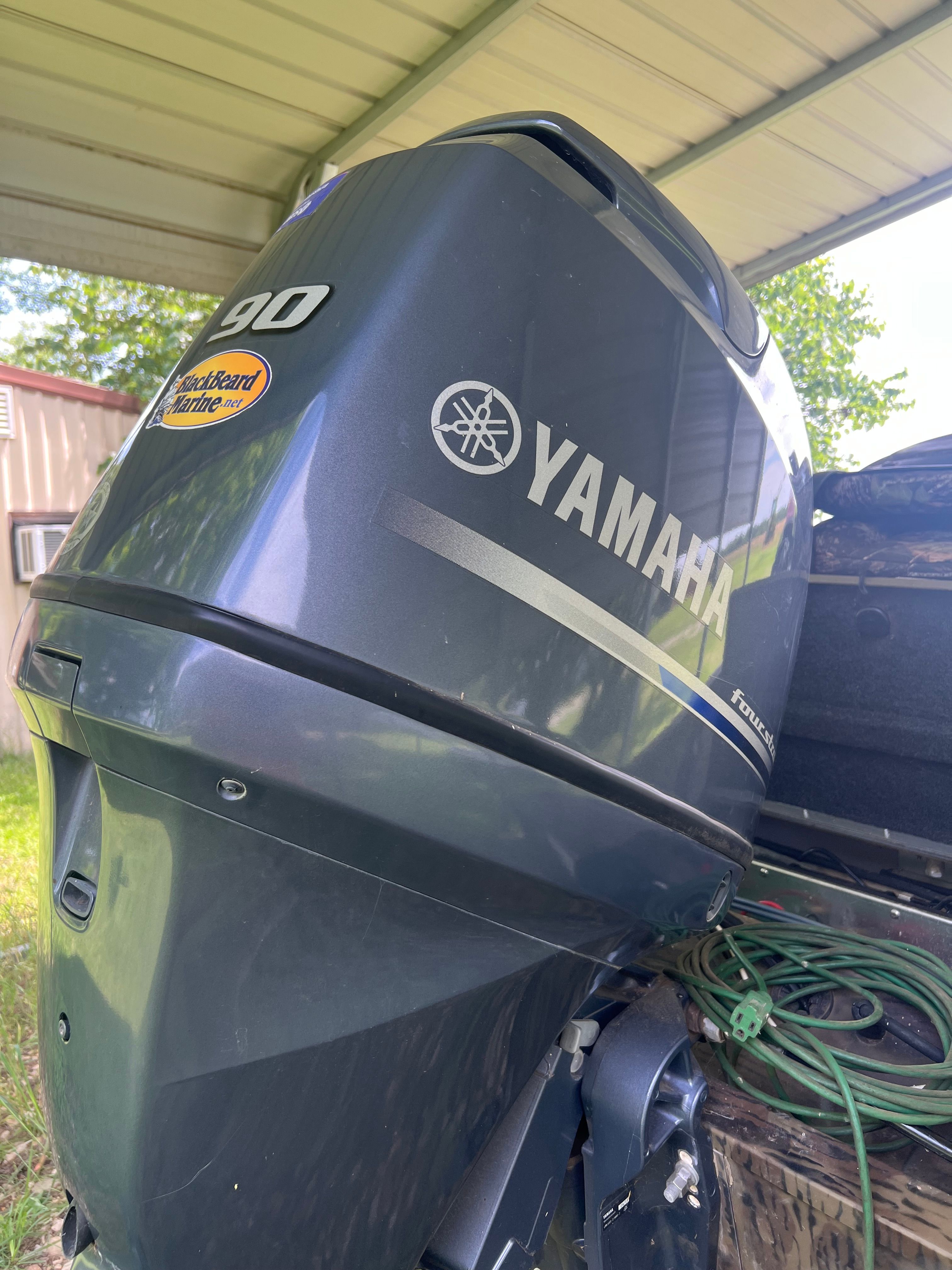 Close-up of a Yamaha outboard motor on a boat, surrounded by green vegetation.