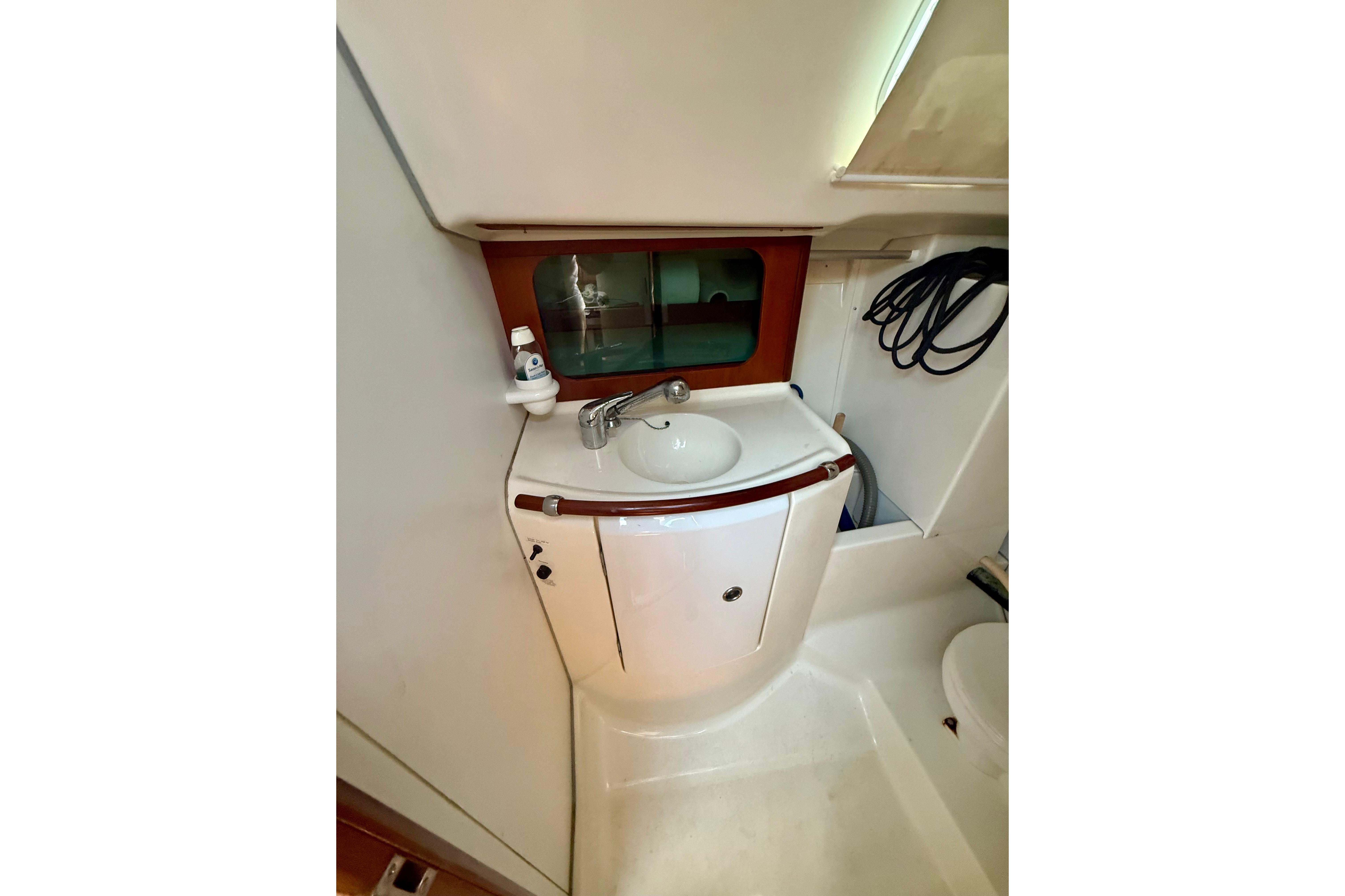 Compact bathroom in 2002 Beneteau Oceanis Clipper 311 yacht, featuring sink and storage.